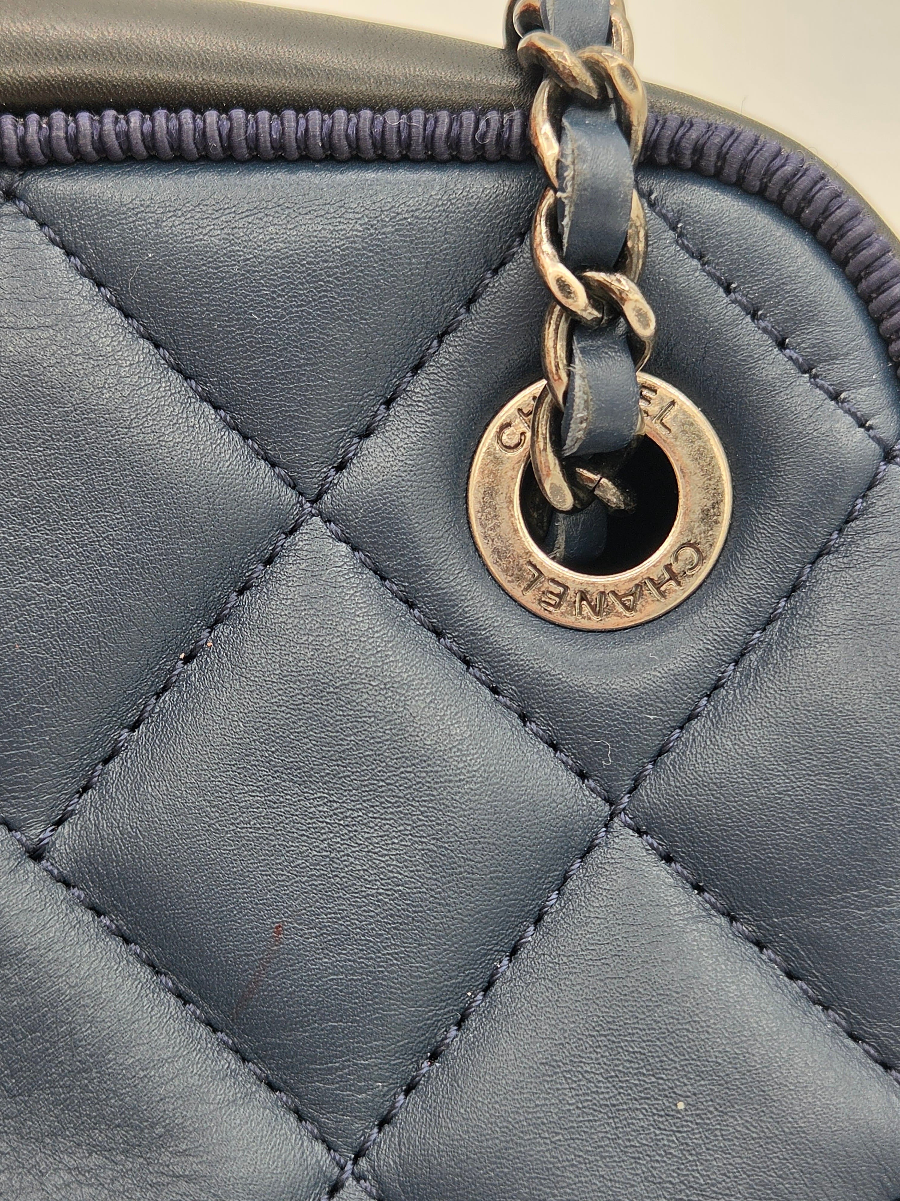 Close-up of a quilted gray handbag with a gold Chanel logo tag.