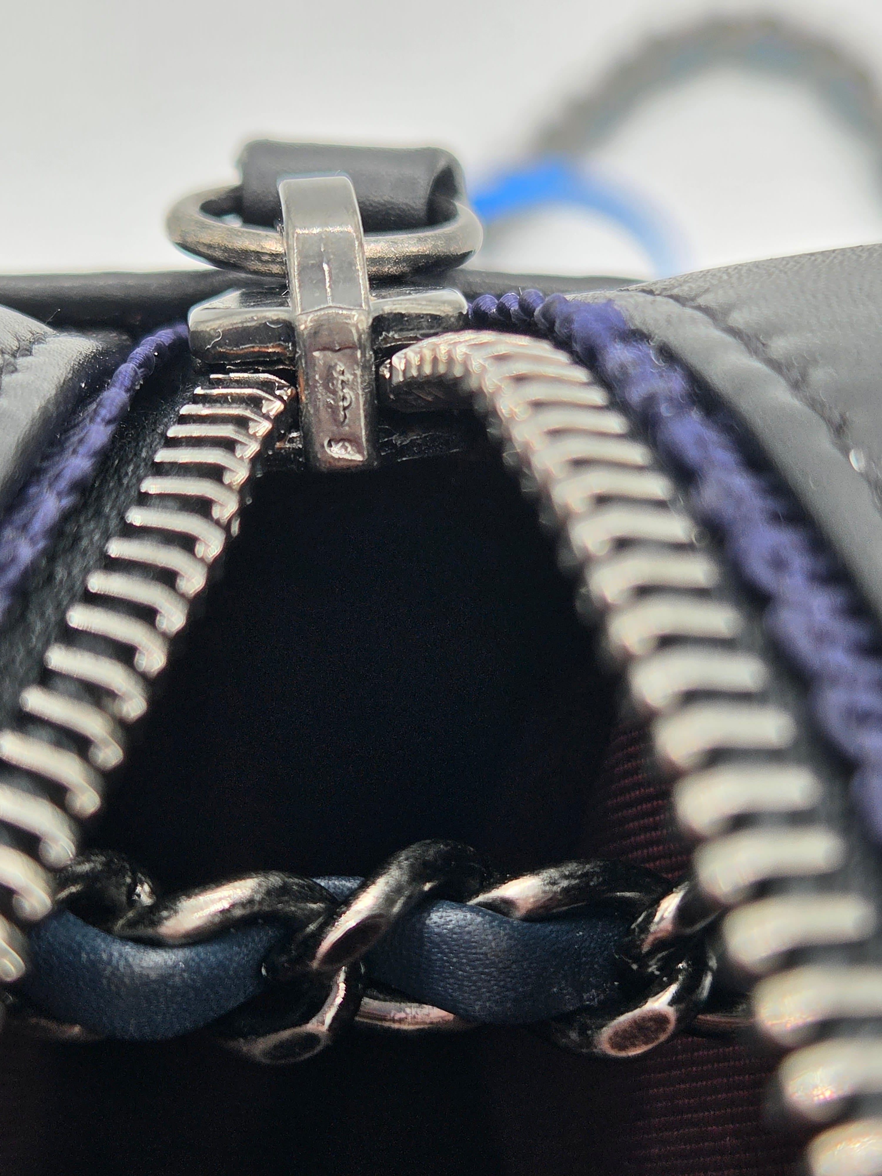 Close-up of a zipper on a black leather bag with a metallic clasp.