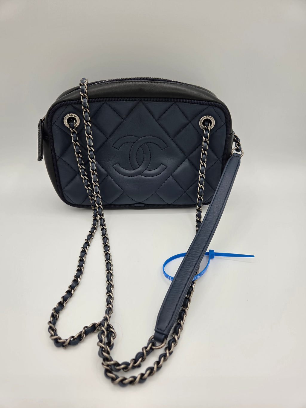 Black quilted handbag with chain strap on a light gray background