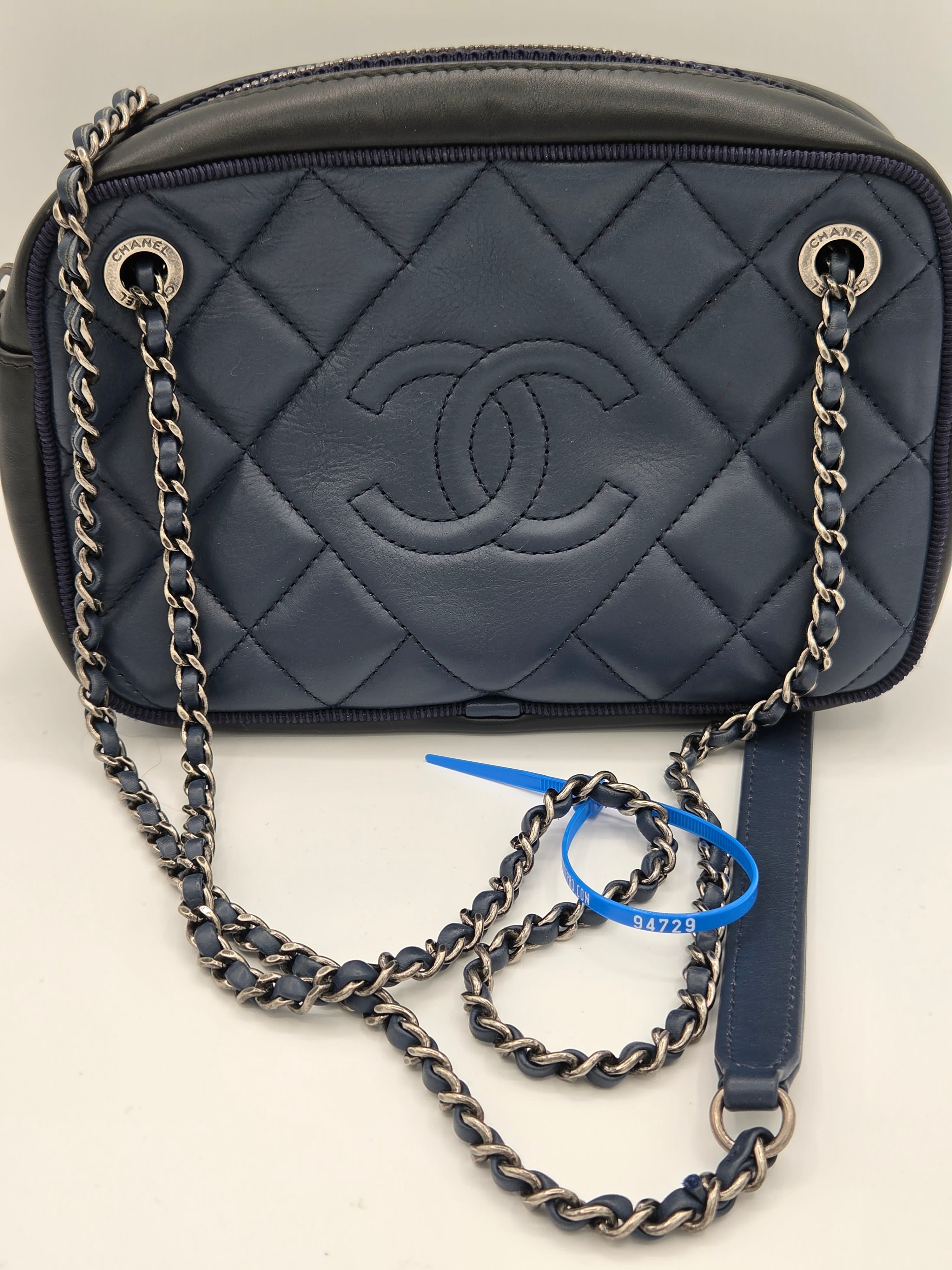 Black quilted handbag with chain strap on a light beige background