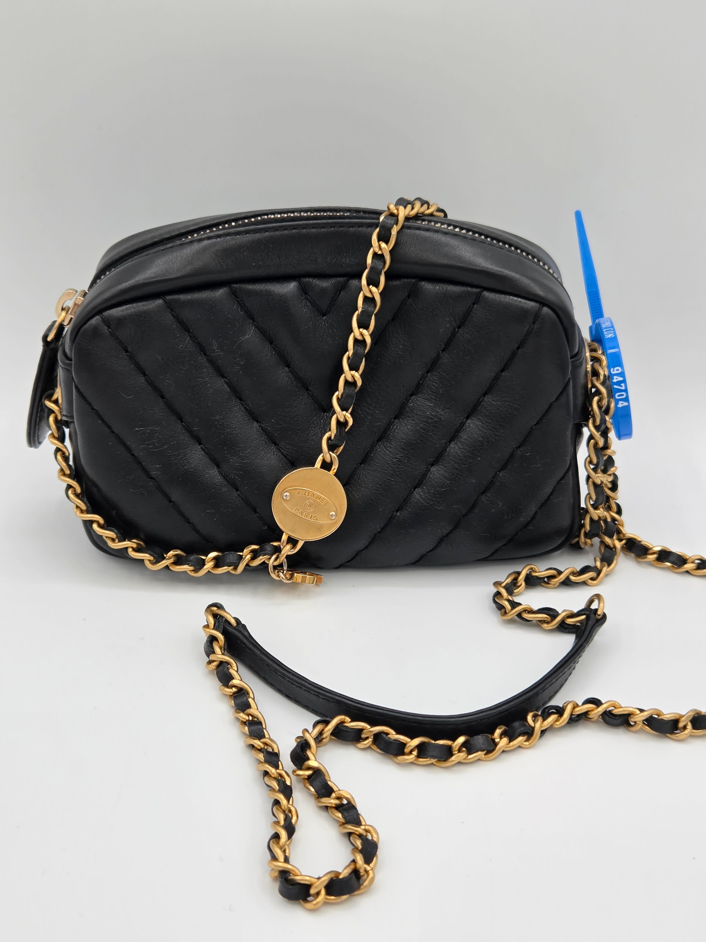 Black quilted handbag with gold chain strap on a light gray background