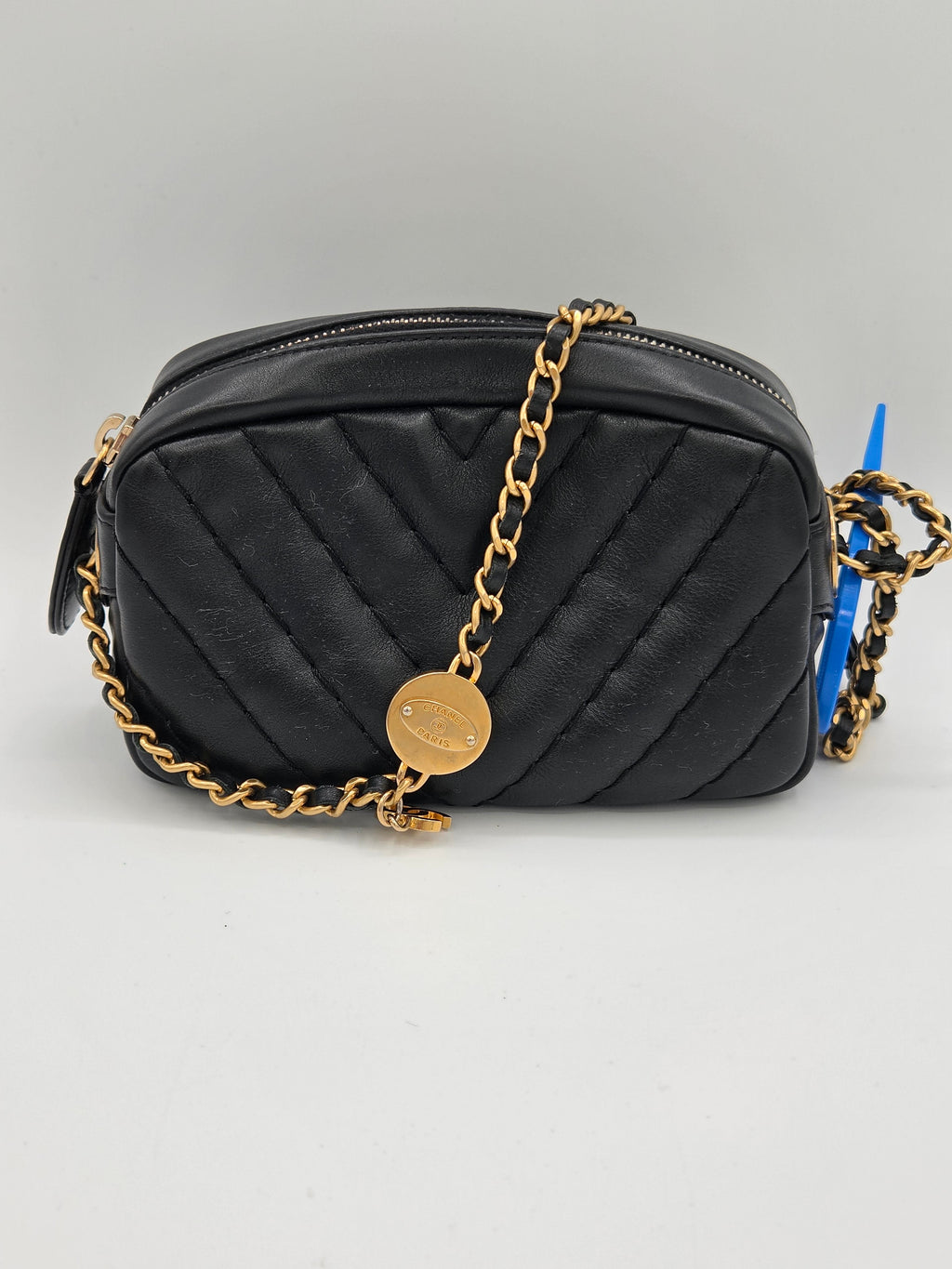 Black quilted handbag with a gold chain on a light gray background
