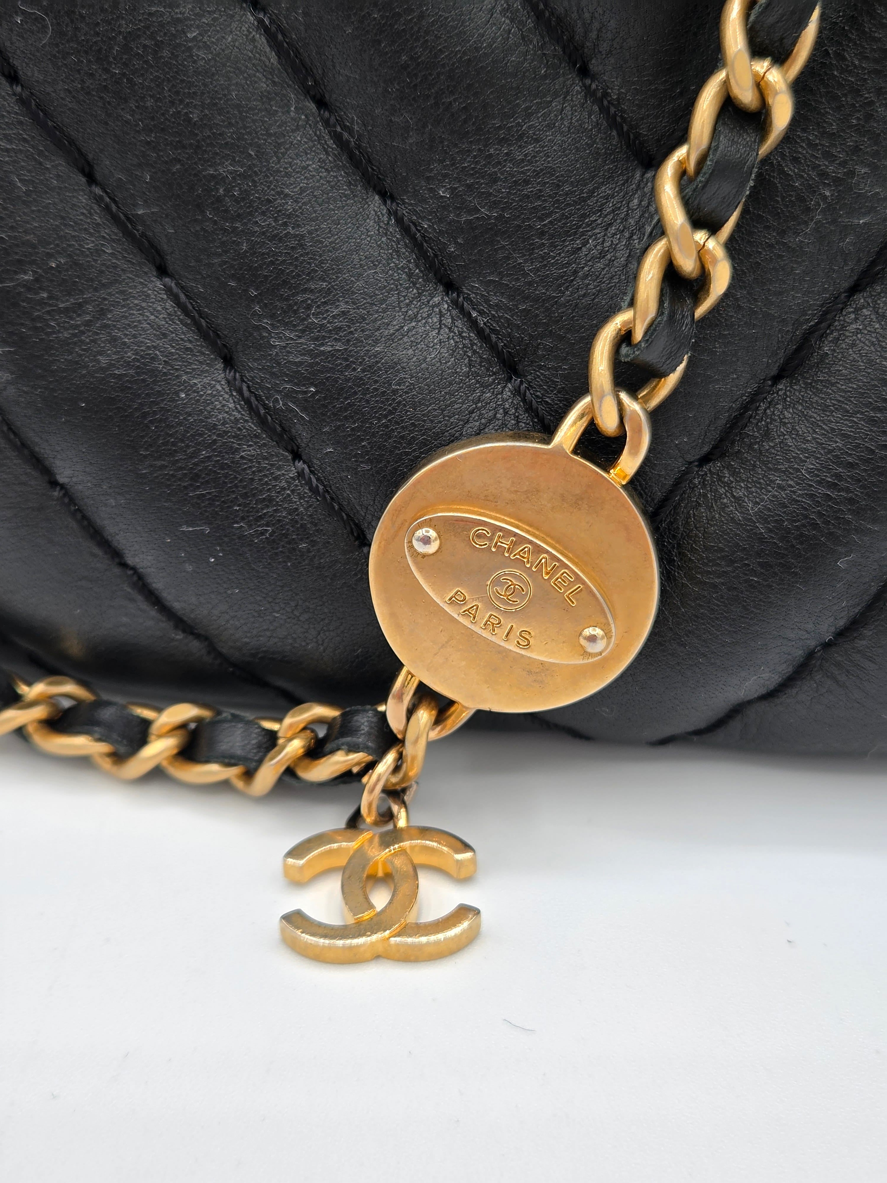 Gold chain with a round tag on a black quilted surface