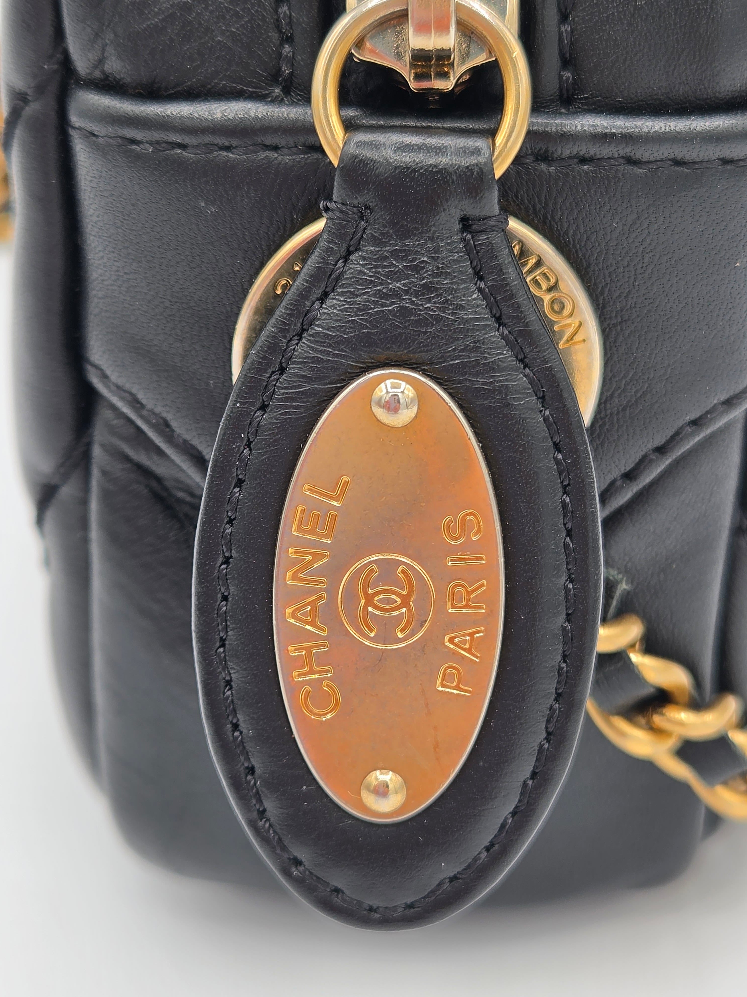 Close-up of a Chanel handbag with gold hardware on a light gray background