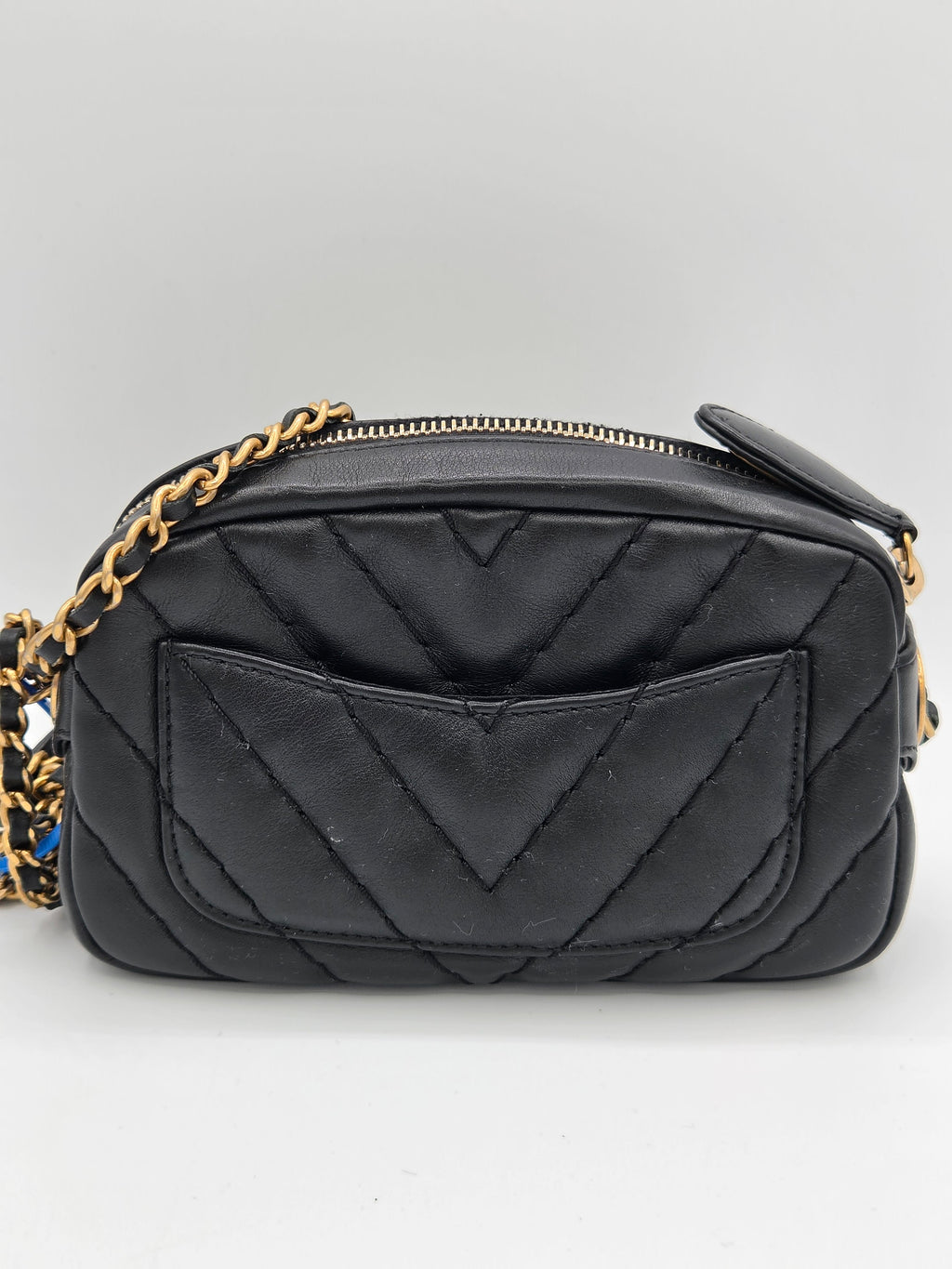 Black quilted handbag with gold chain strap on a light gray background