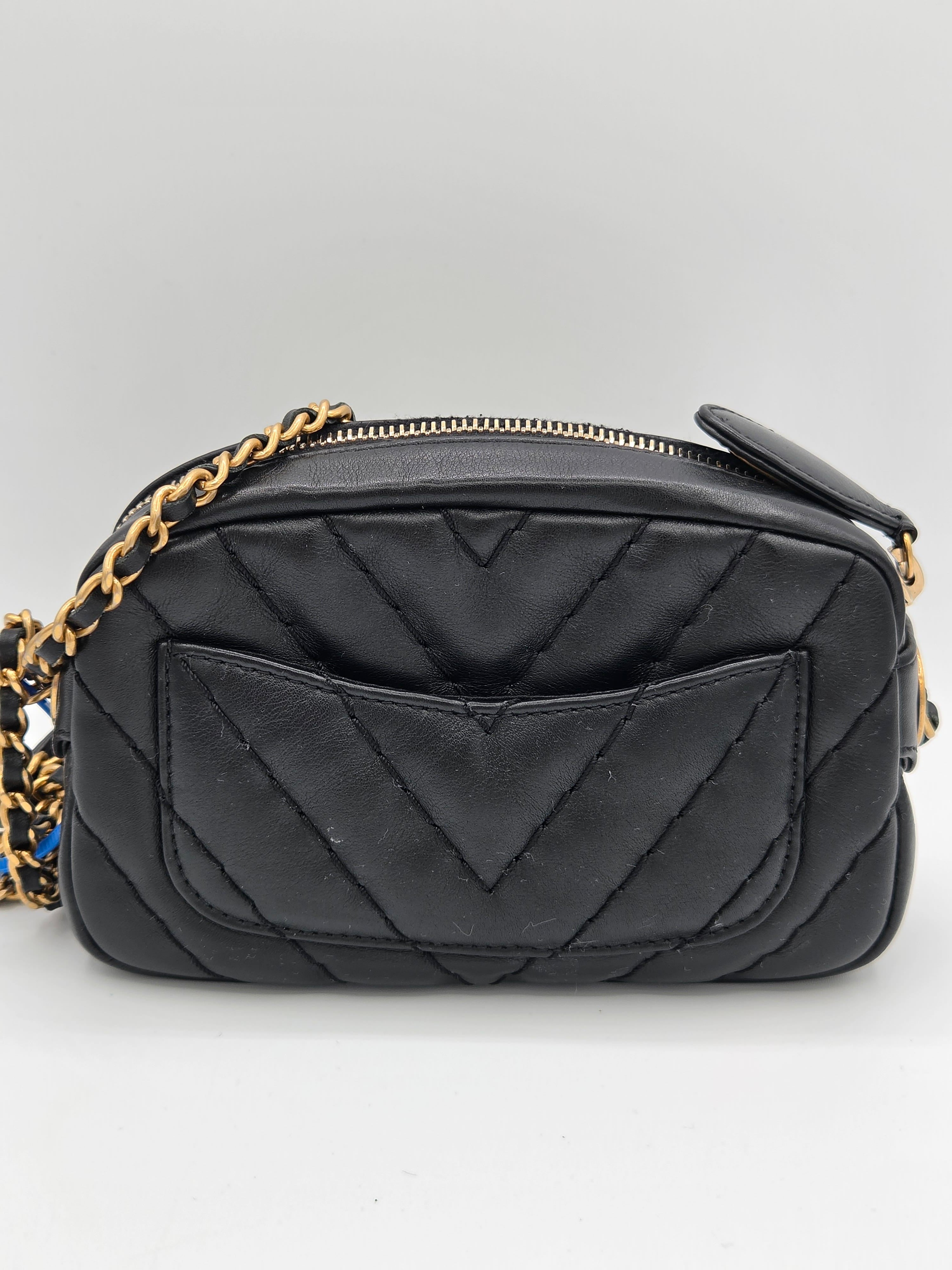 Black quilted handbag with gold chain strap on a light gray background