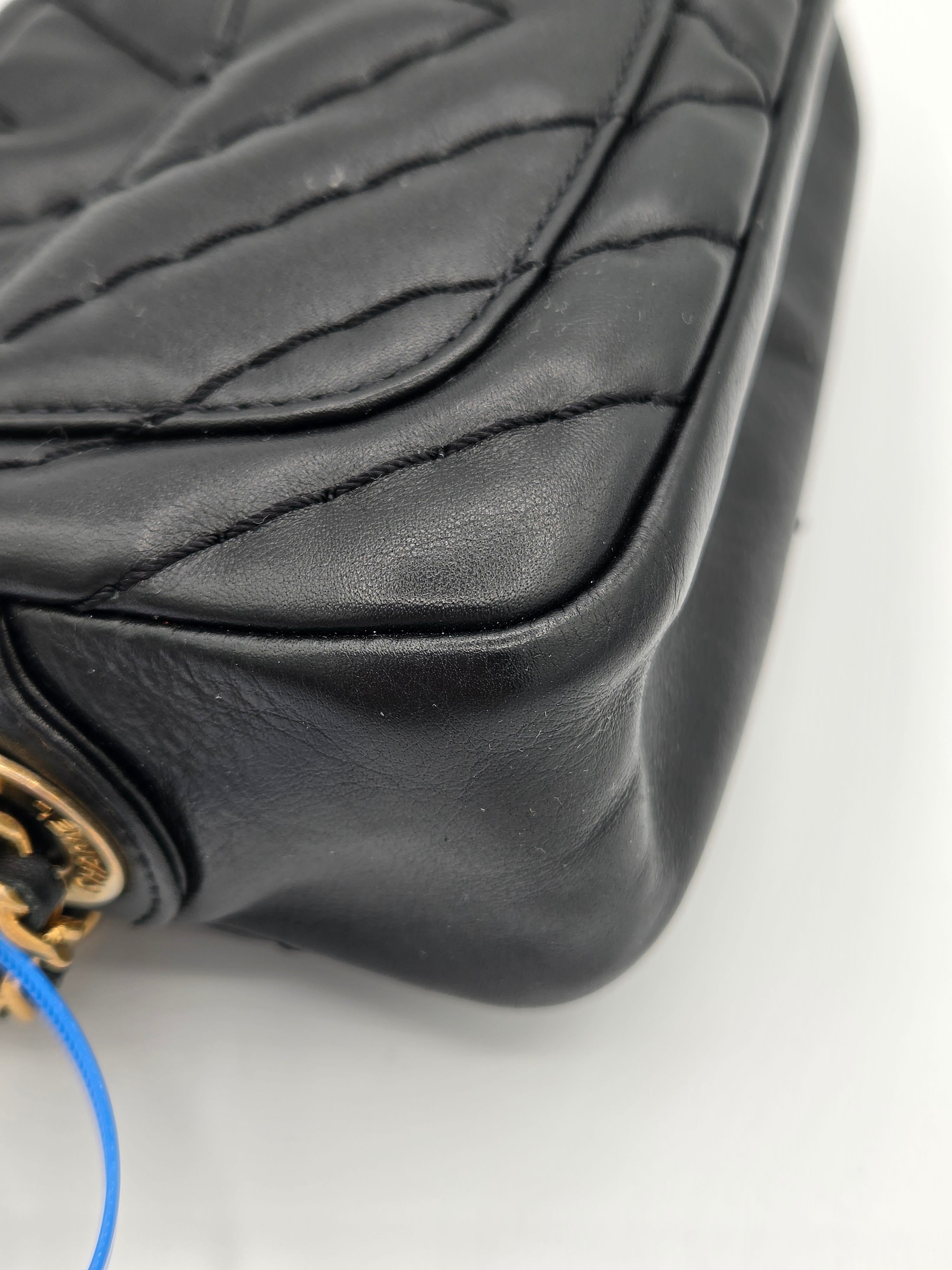 Close-up of a black quilted leather bag with a visible brand logo on a white background