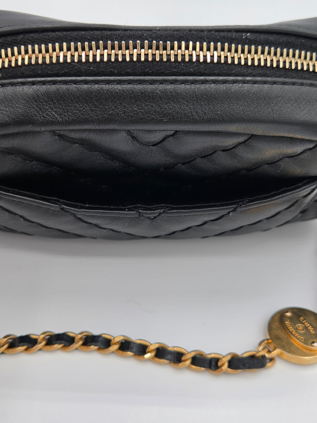 Black leather handbag with gold zipper and chain strap on a white background