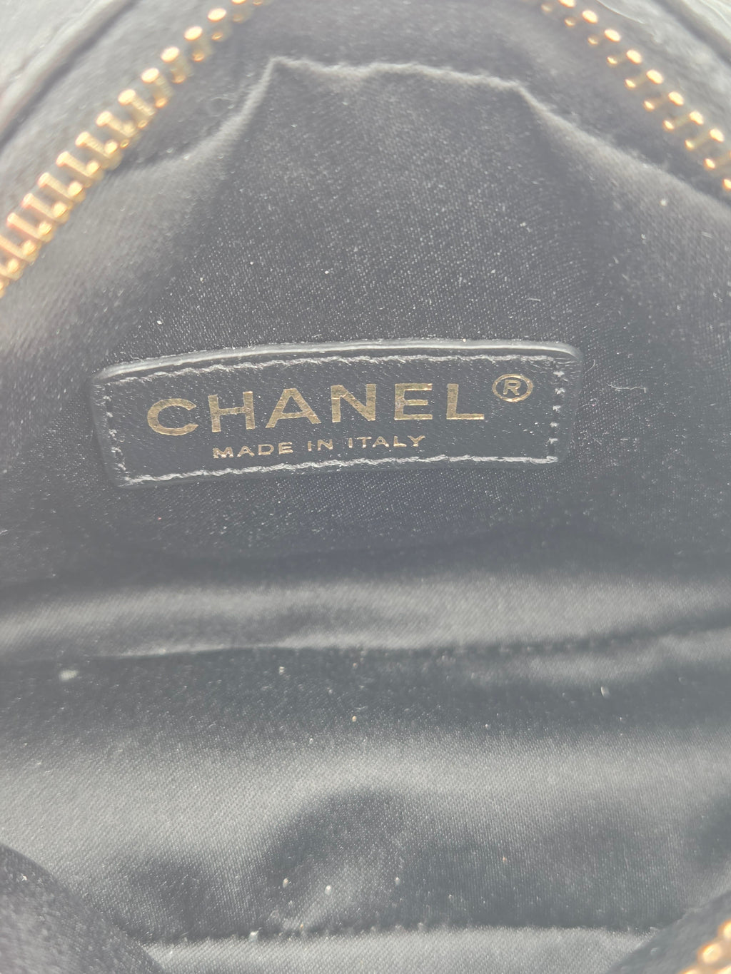 Close-up of a Chanel logo on a black textured surface with gold accents.