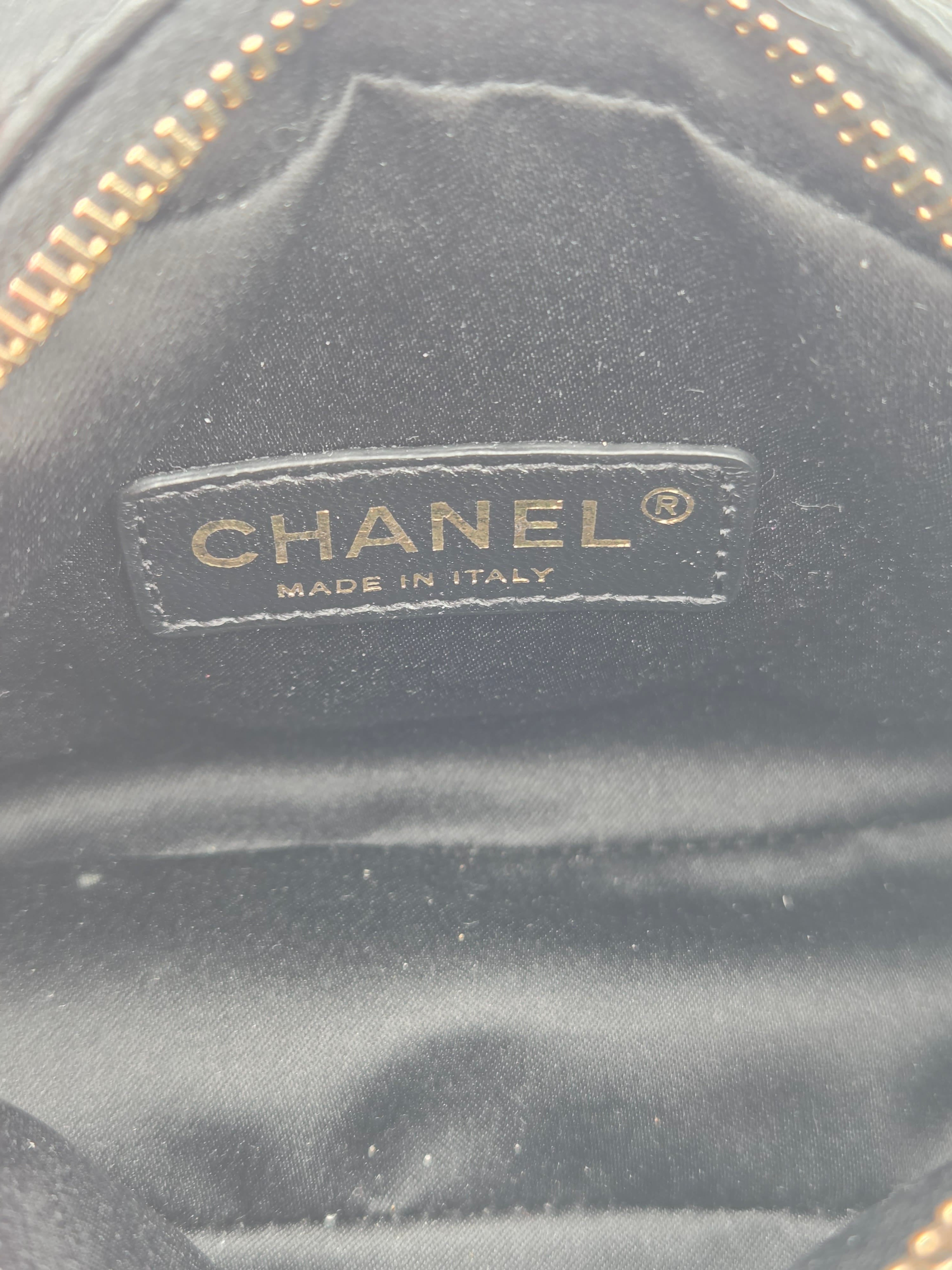 Close-up of a Chanel logo on a black textured surface with gold accents.