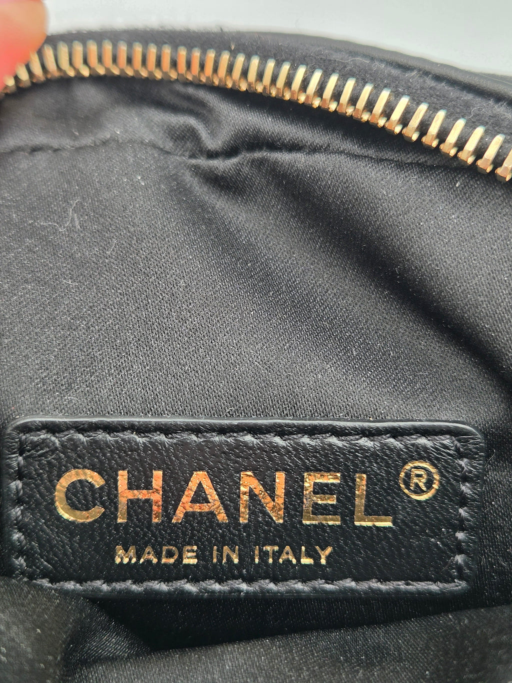 Close-up of a Chanel label on a black leather product with gold lettering.