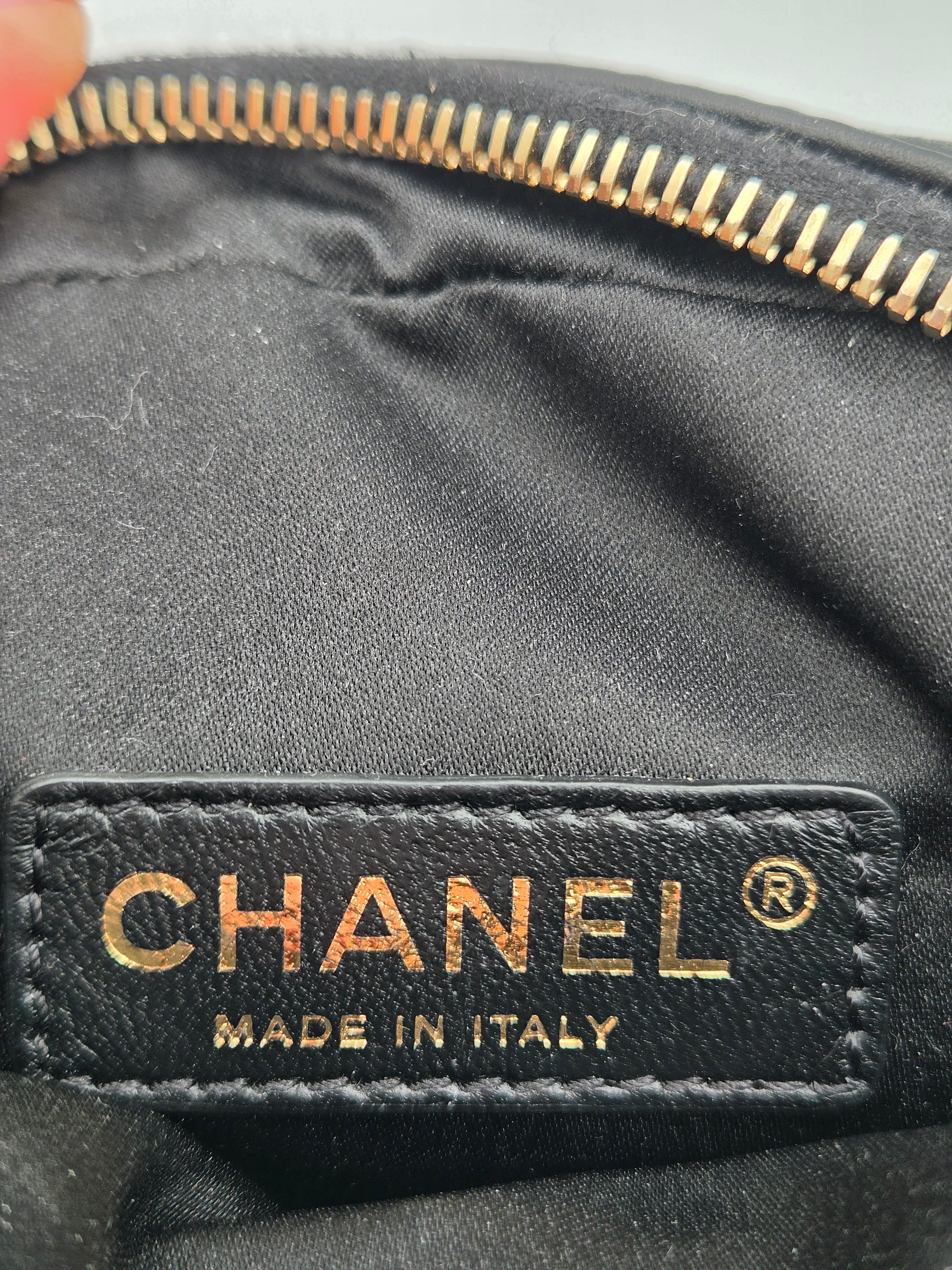 Close-up of a Chanel label on a black leather product with gold lettering.