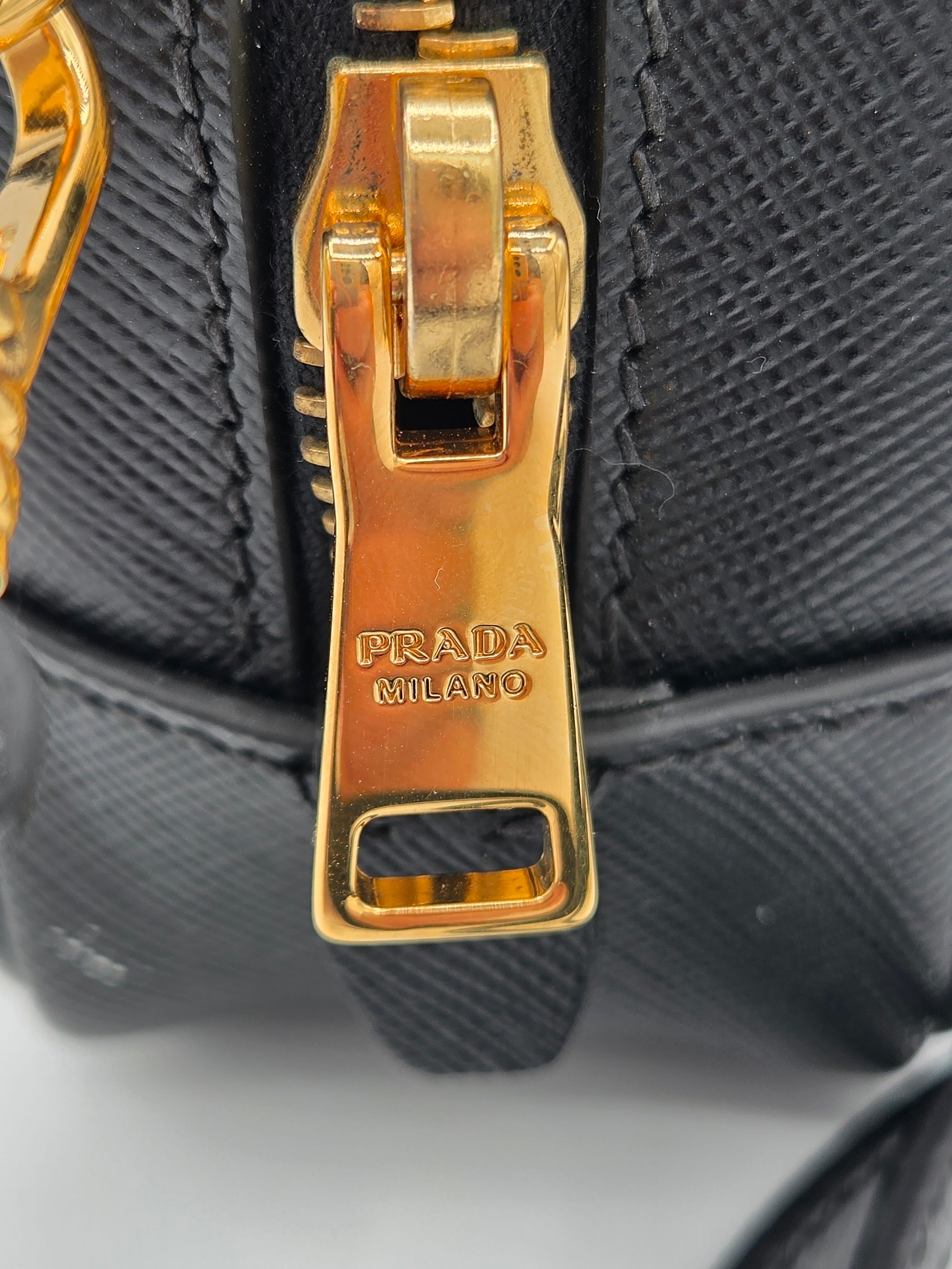 Close-up of a Prada handbag with gold hardware on a black textured background