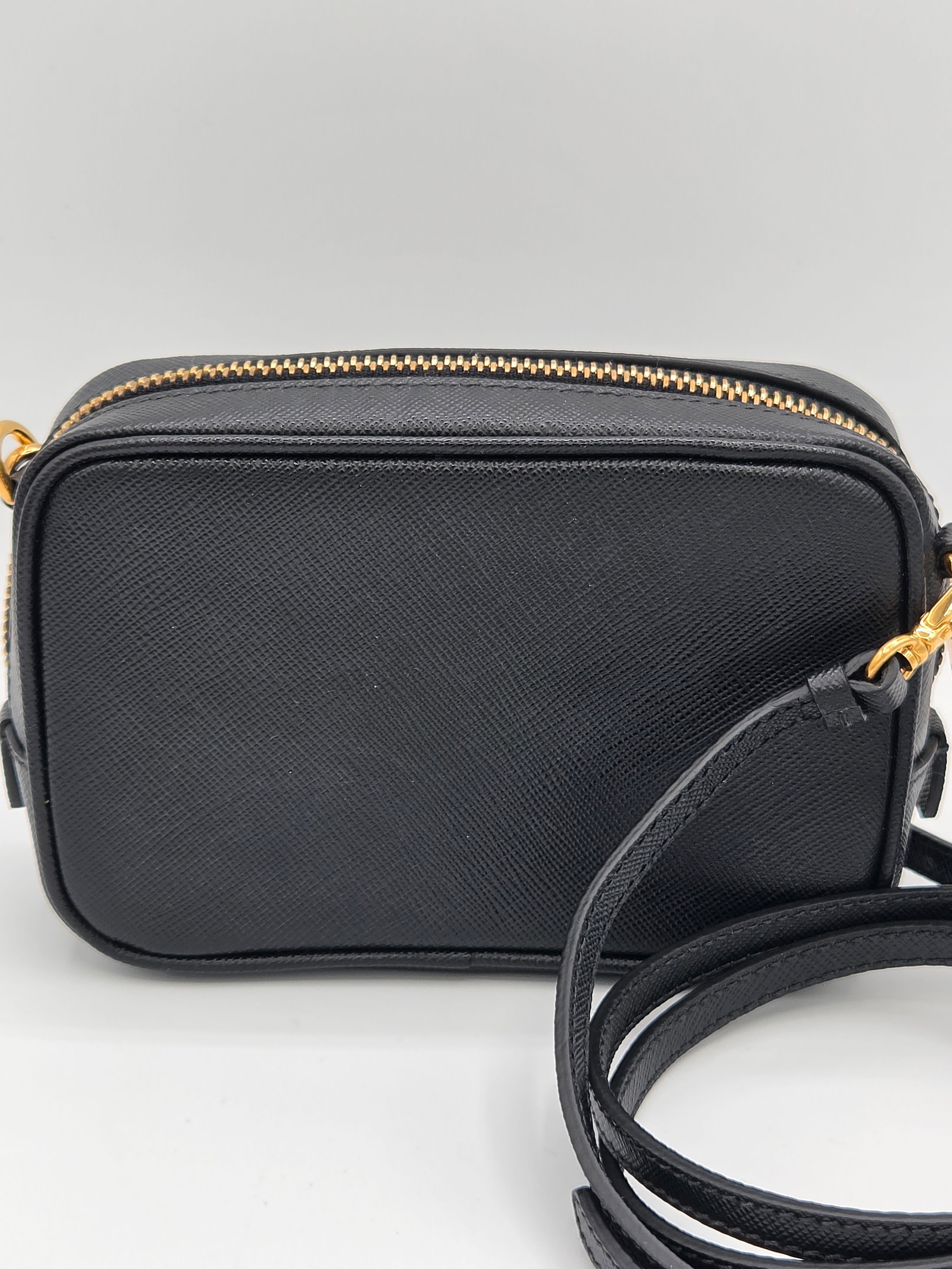 Black crossbody bag with a strap on a light gray background