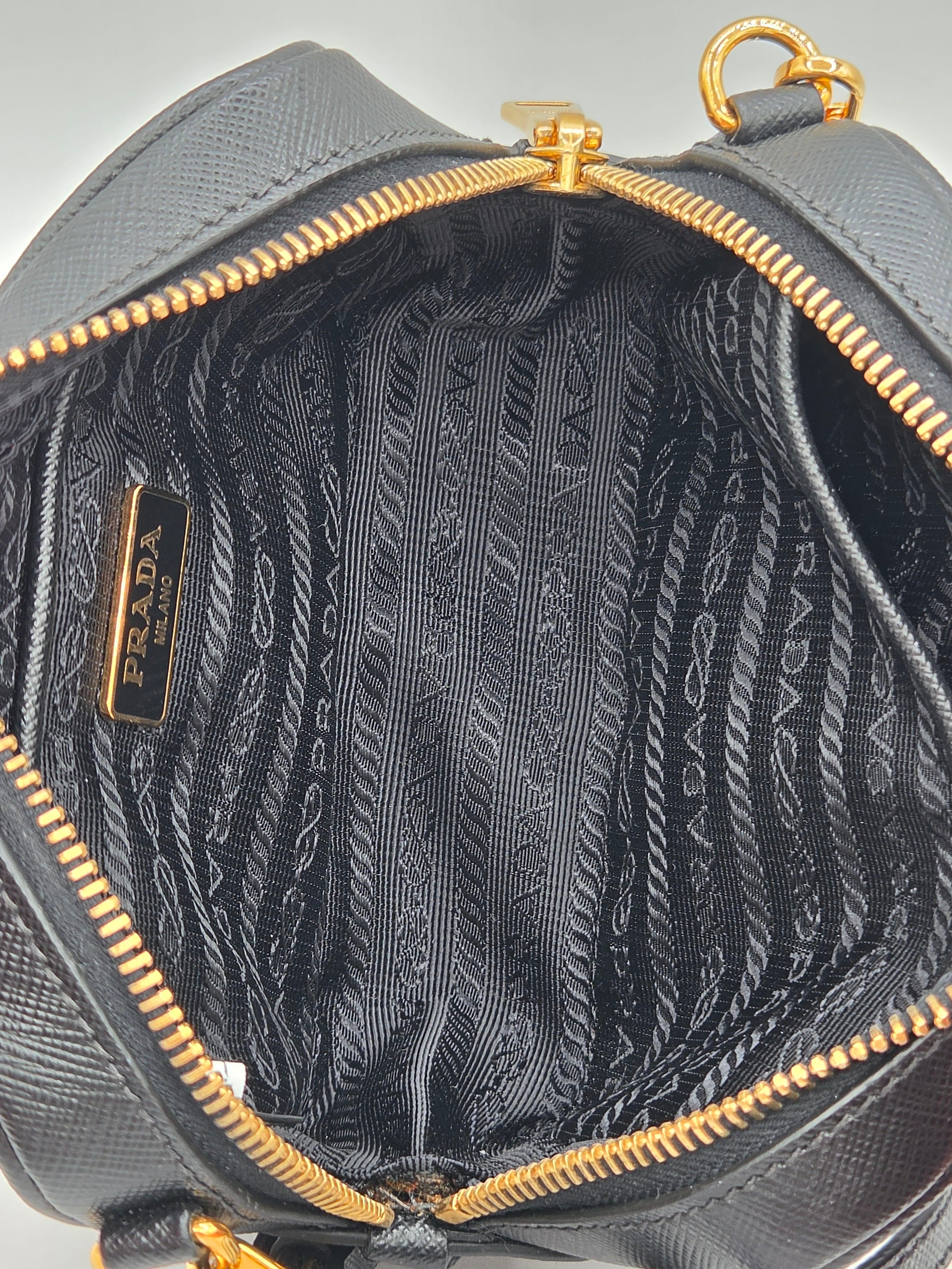 Gray handbag with gold zipper and Prada logo on a light gray background