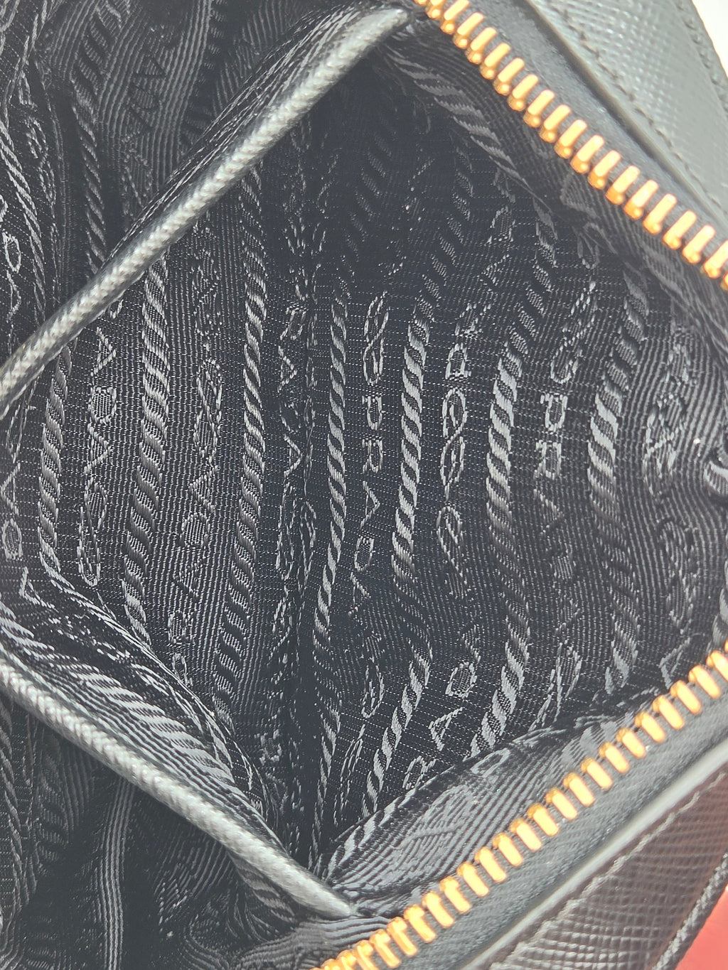 Close-up of a Prada handbag with gold zipper and textured fabric.