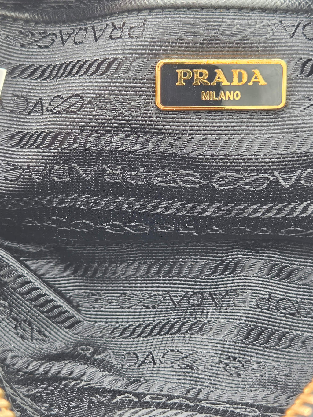 Close-up of a Prada handbag with gold logo on a textured fabric background