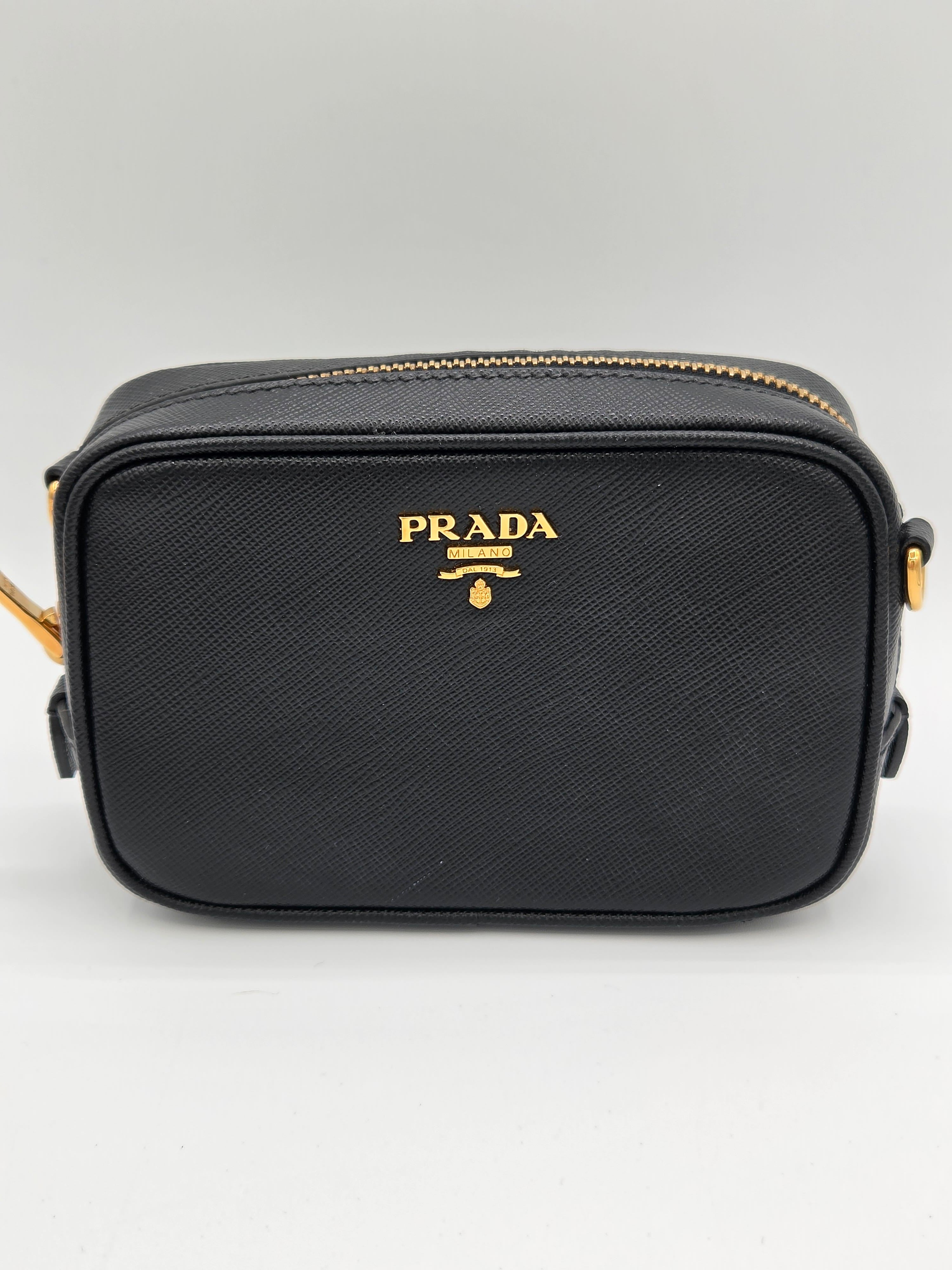 Black Prada handbag with gold accents on a light gray background