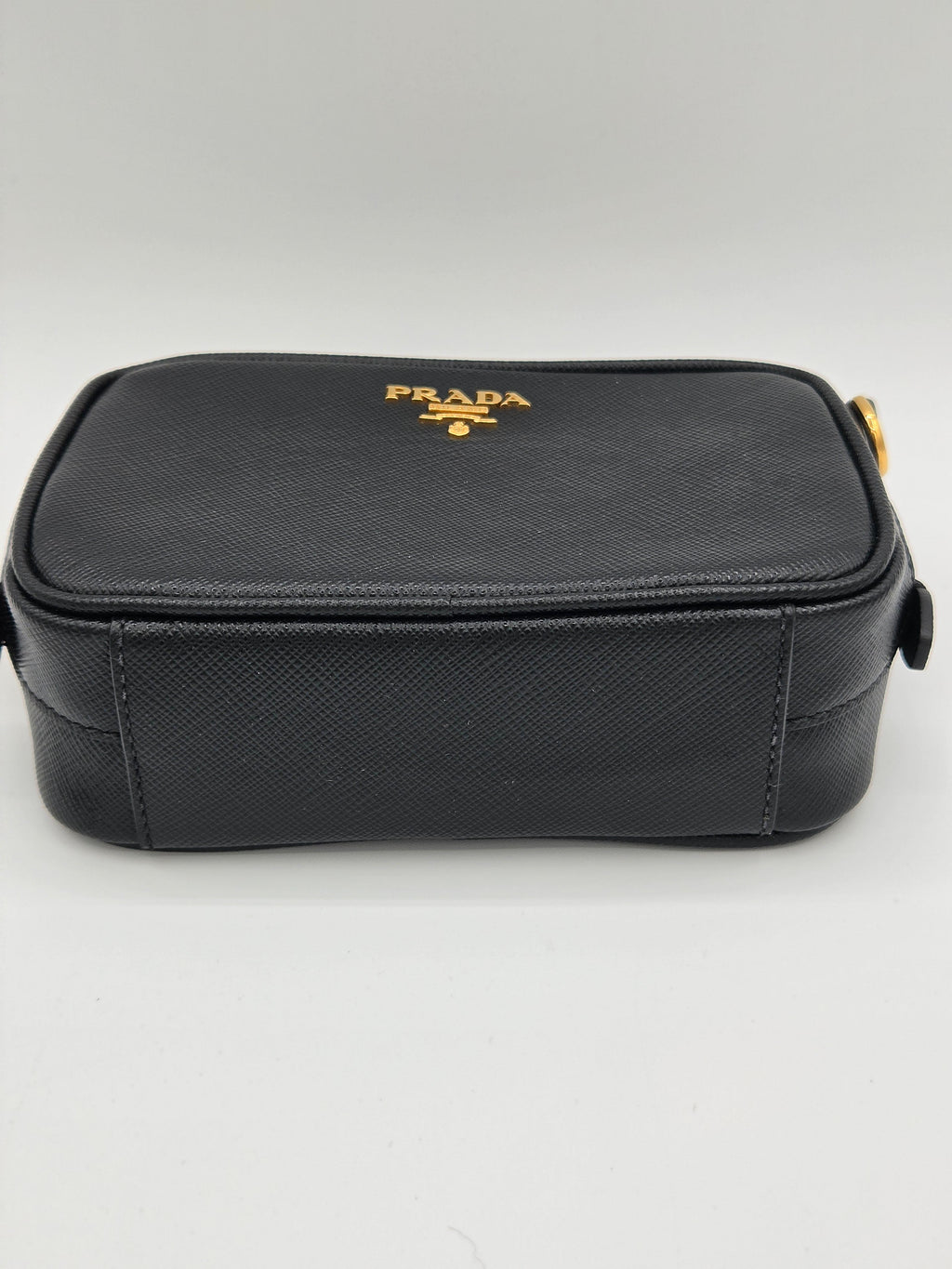 Black rectangular pouch with a gold logo on a light gray background