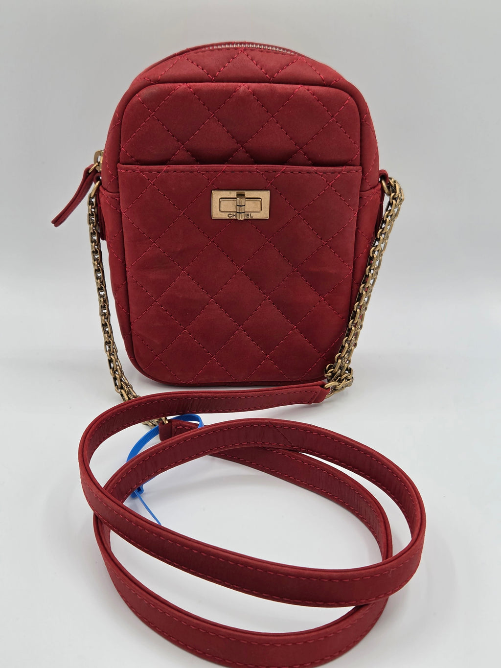 Red quilted handbag with a chain strap on a light gray background