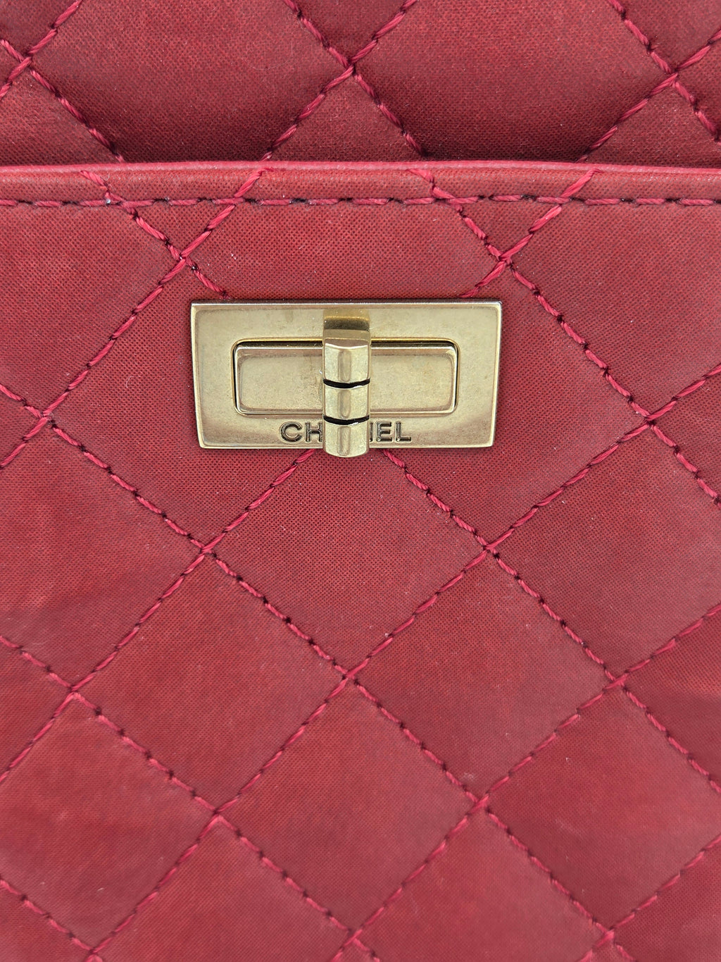 Close-up of a red quilted handbag with a gold clasp.