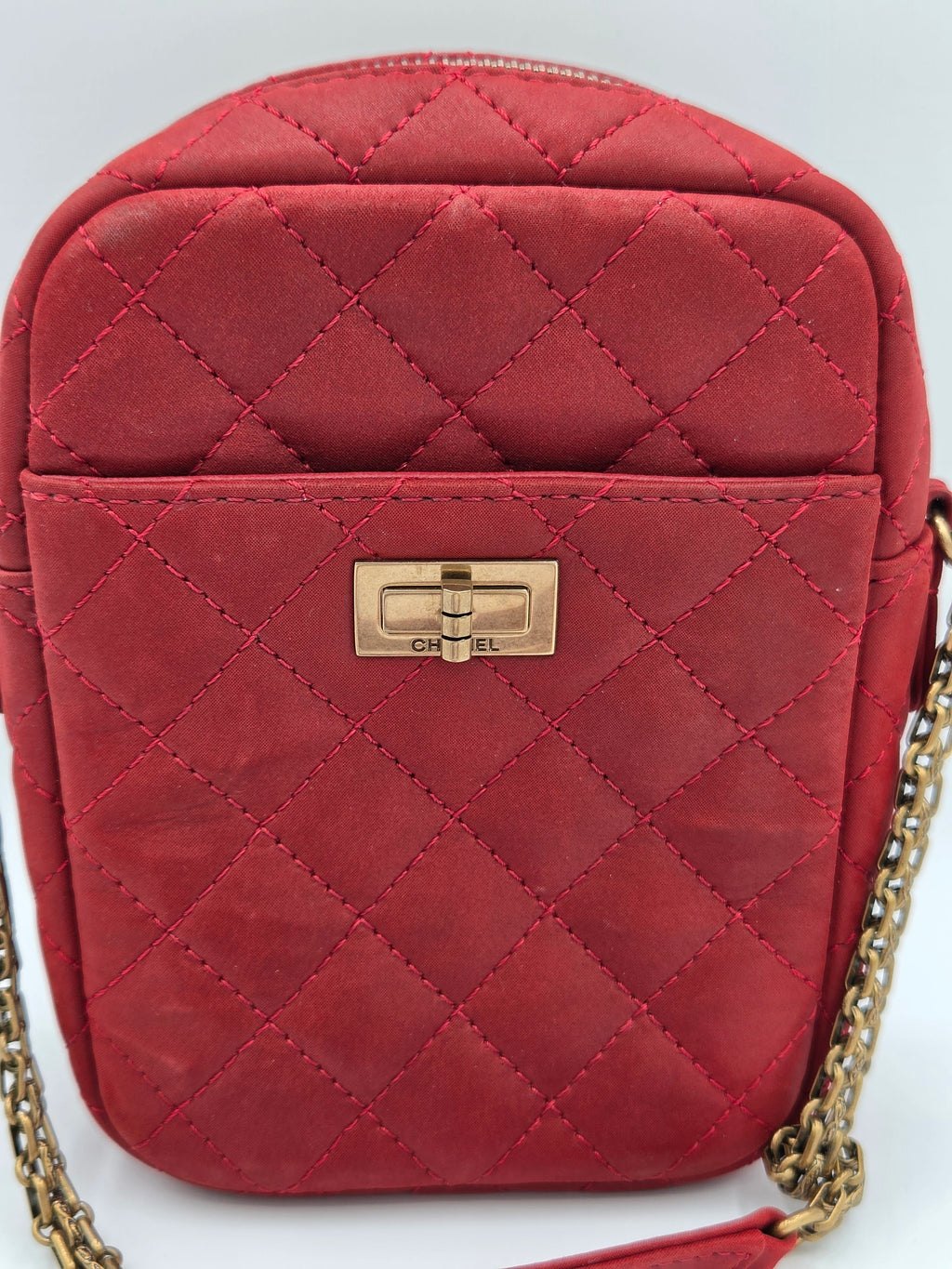 Red quilted handbag with a gold chain on a white background