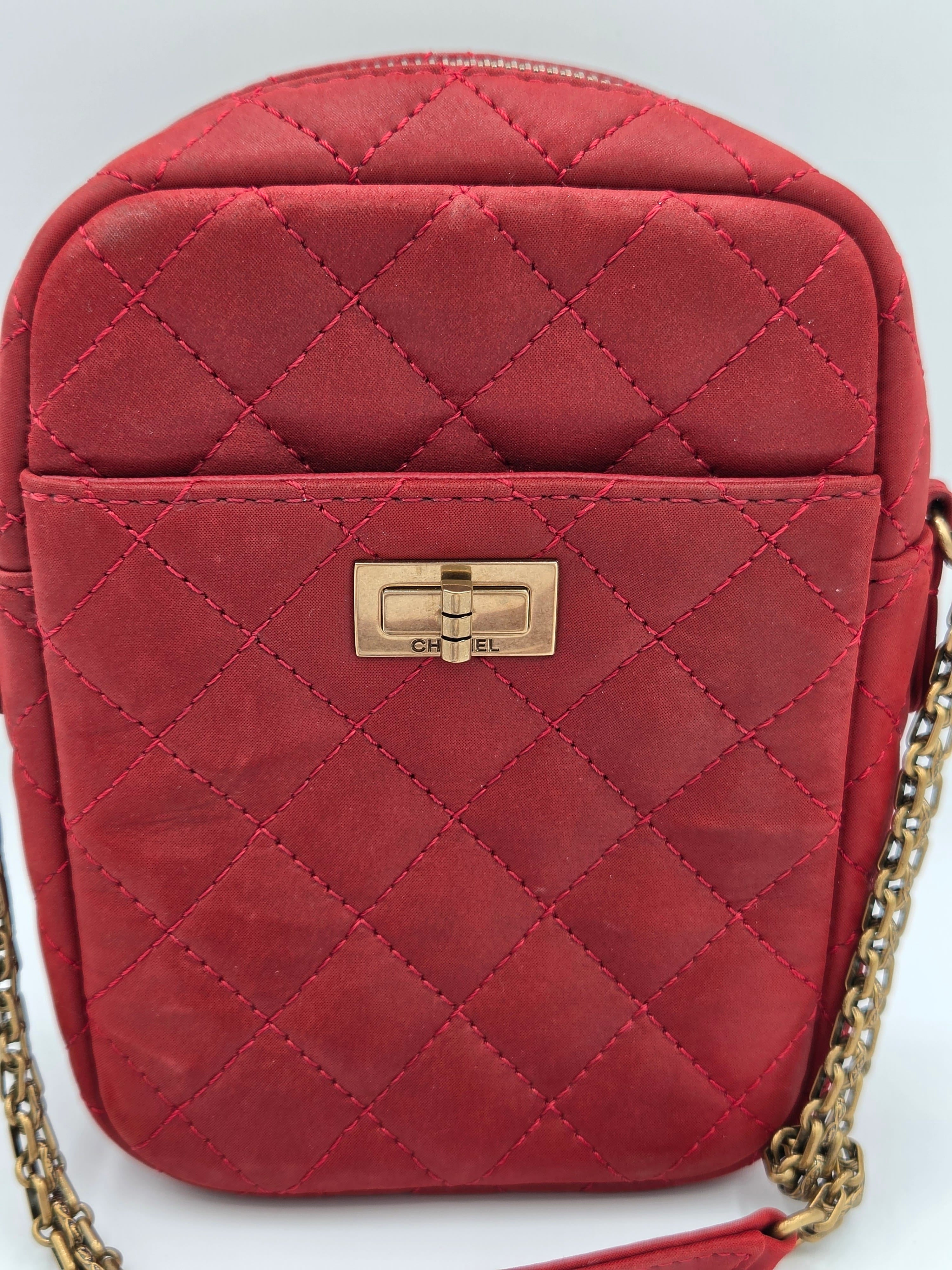 Red quilted handbag with a gold chain on a white background