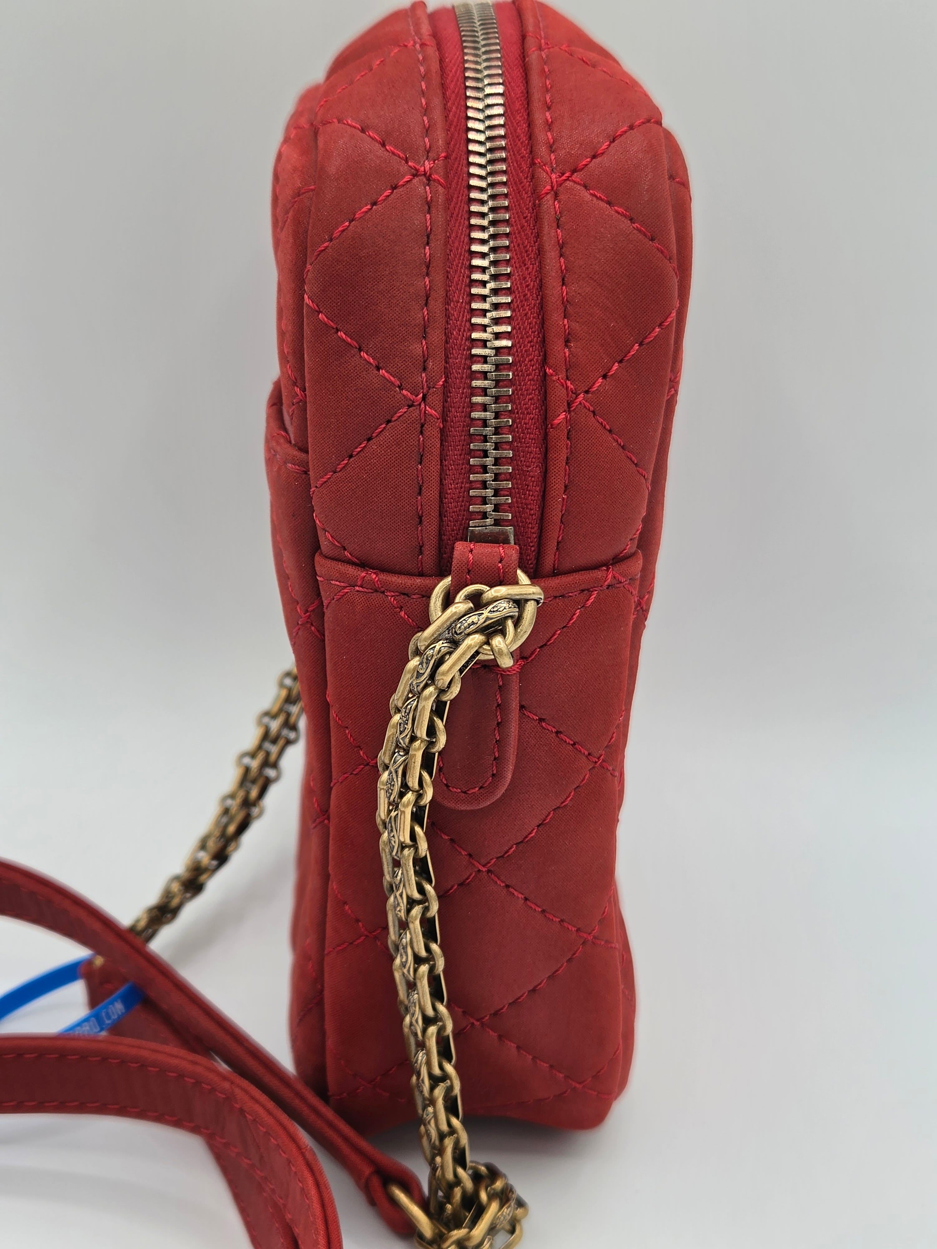 Red quilted handbag with gold chain strap on a light gray background