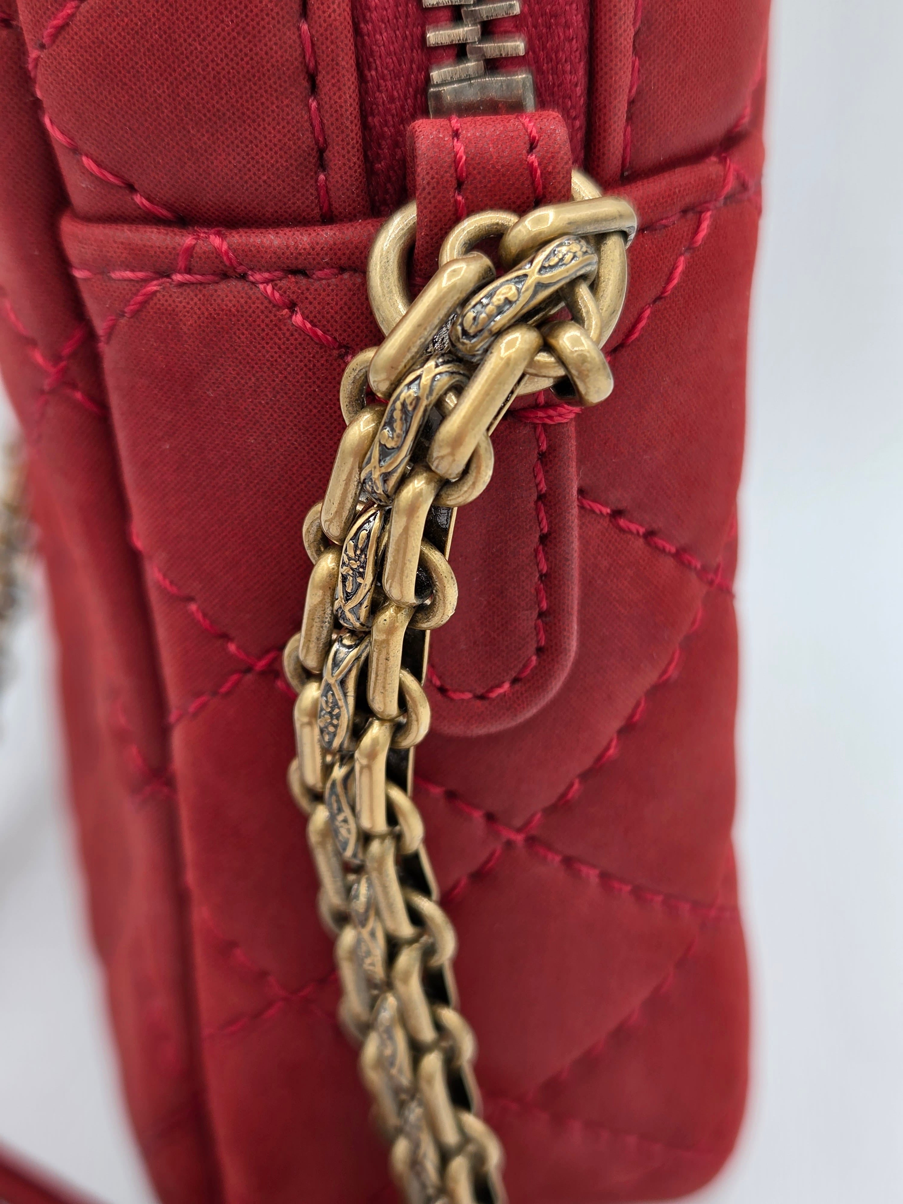 Red quilted handbag with a gold chain handle on a white background