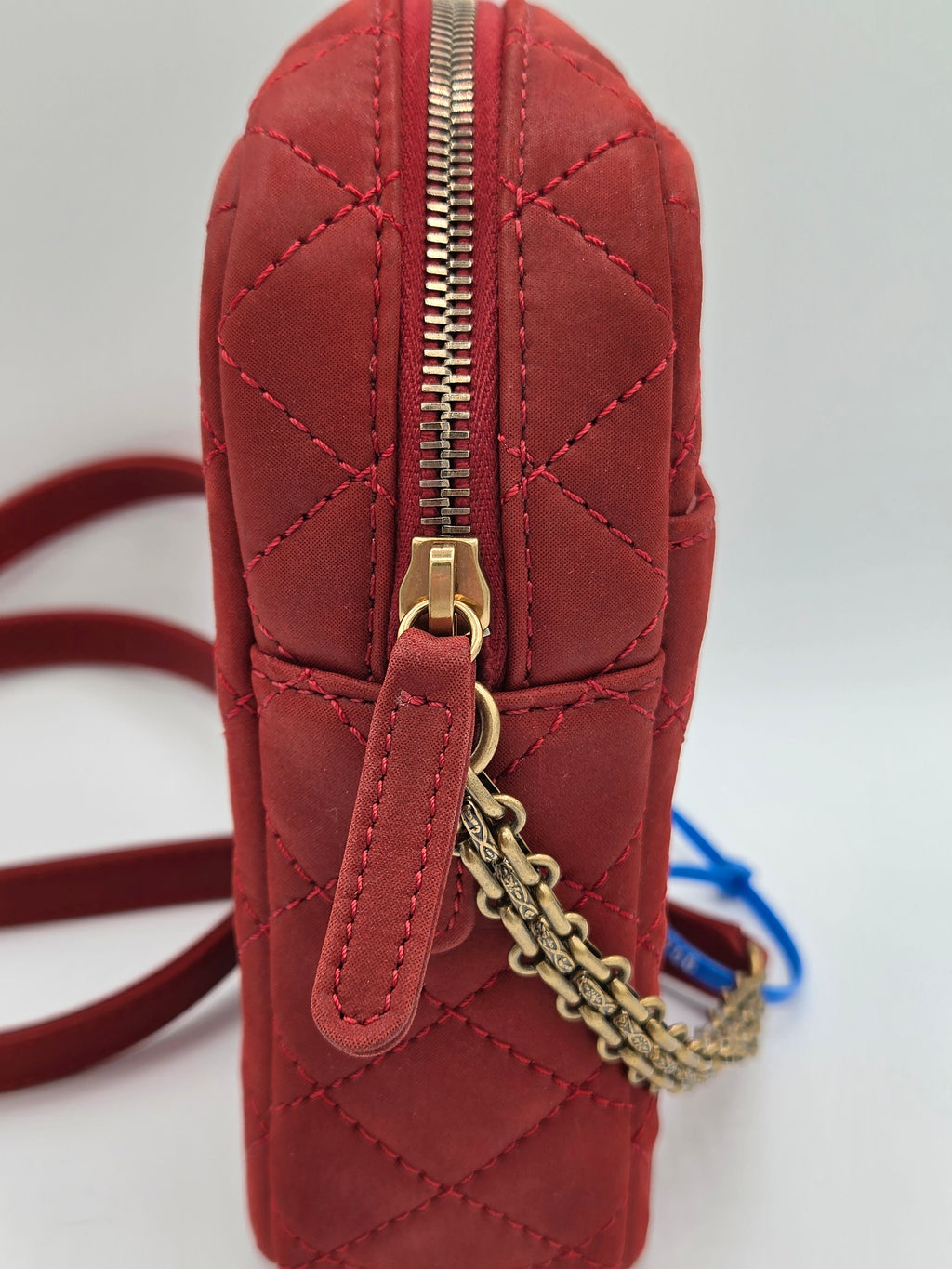 Red quilted handbag with gold chain strap on a white background