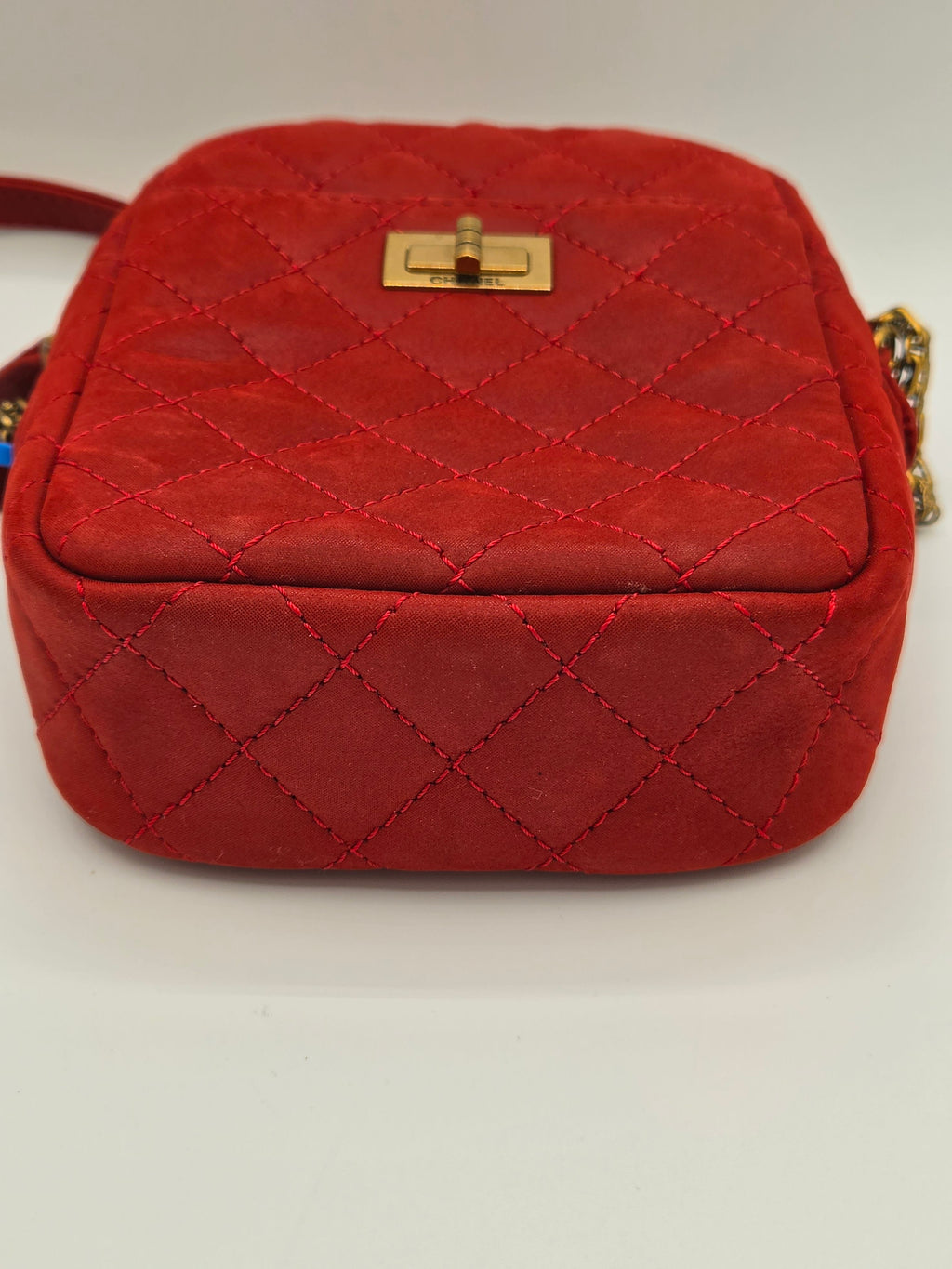 Red quilted handbag with gold clasp on a light gray background