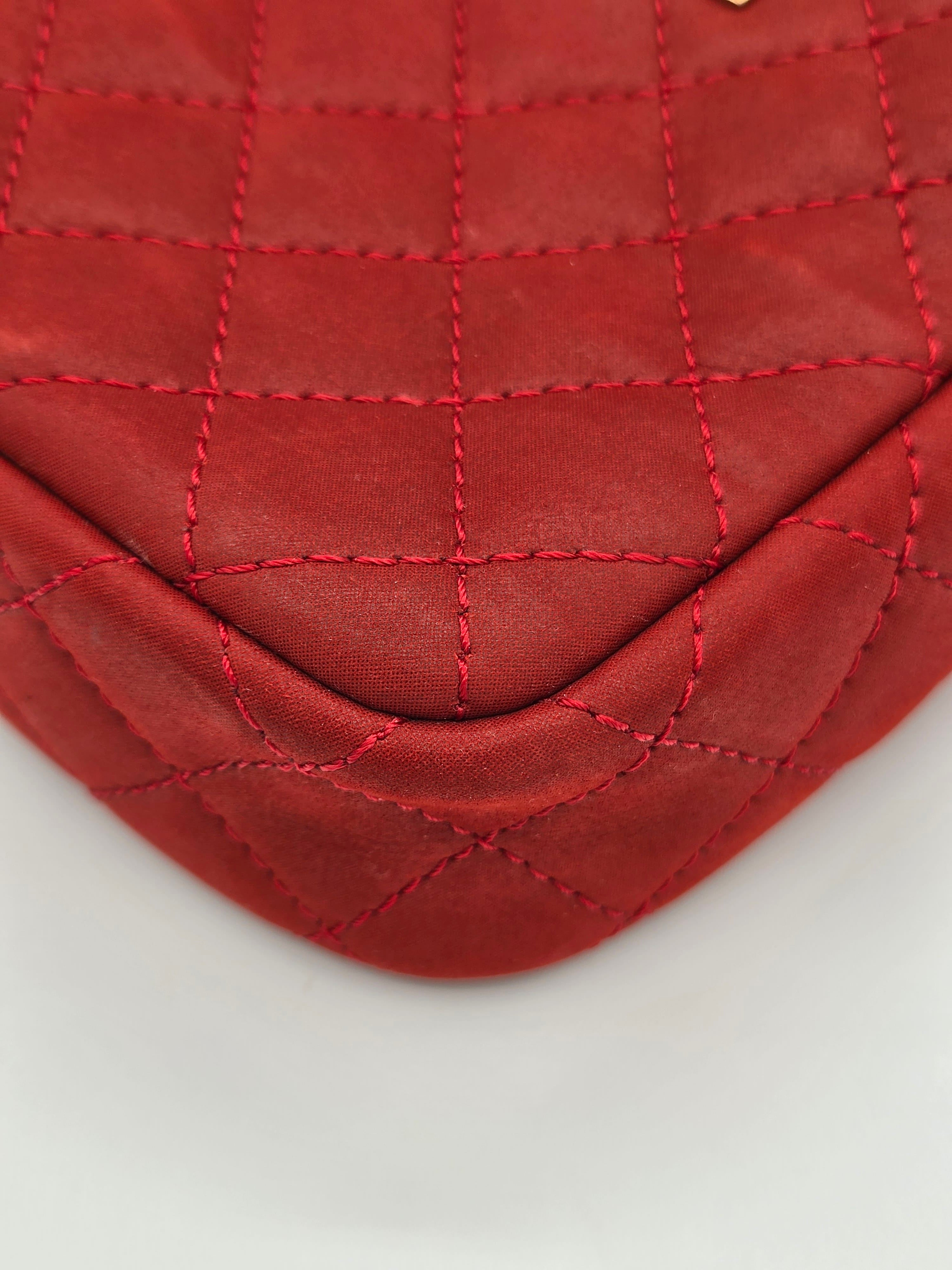Red quilted fabric with visible stitching on a light gray background