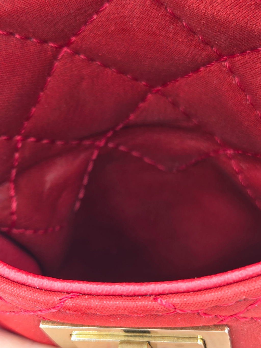 Close-up of a red quilted handbag with a gold clasp.
