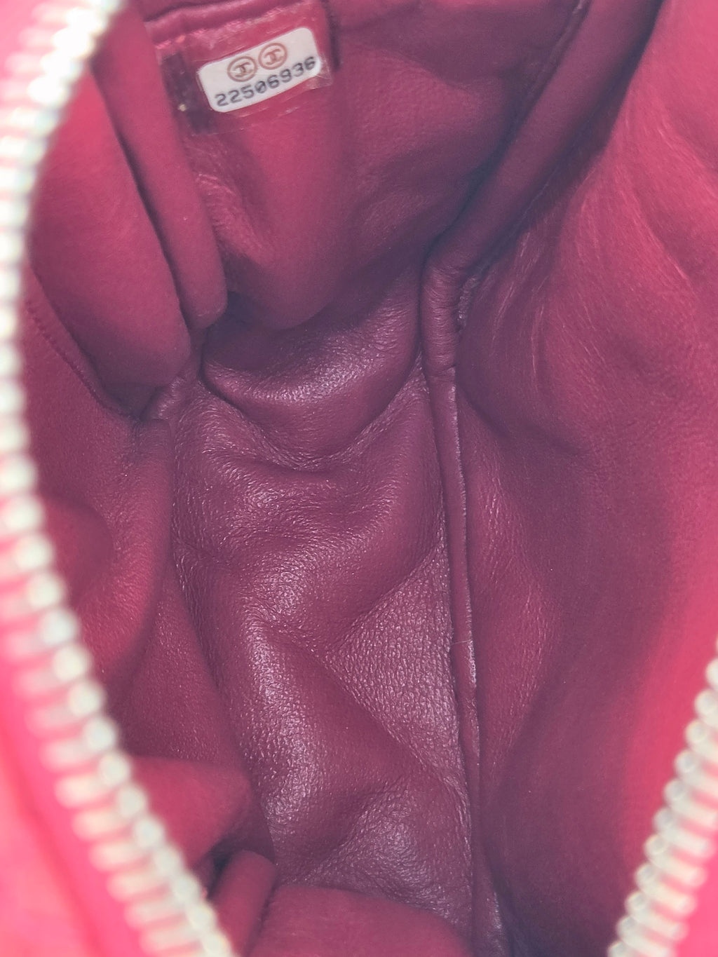 Close-up of a maroon quilted leather bag with a visible brand label.