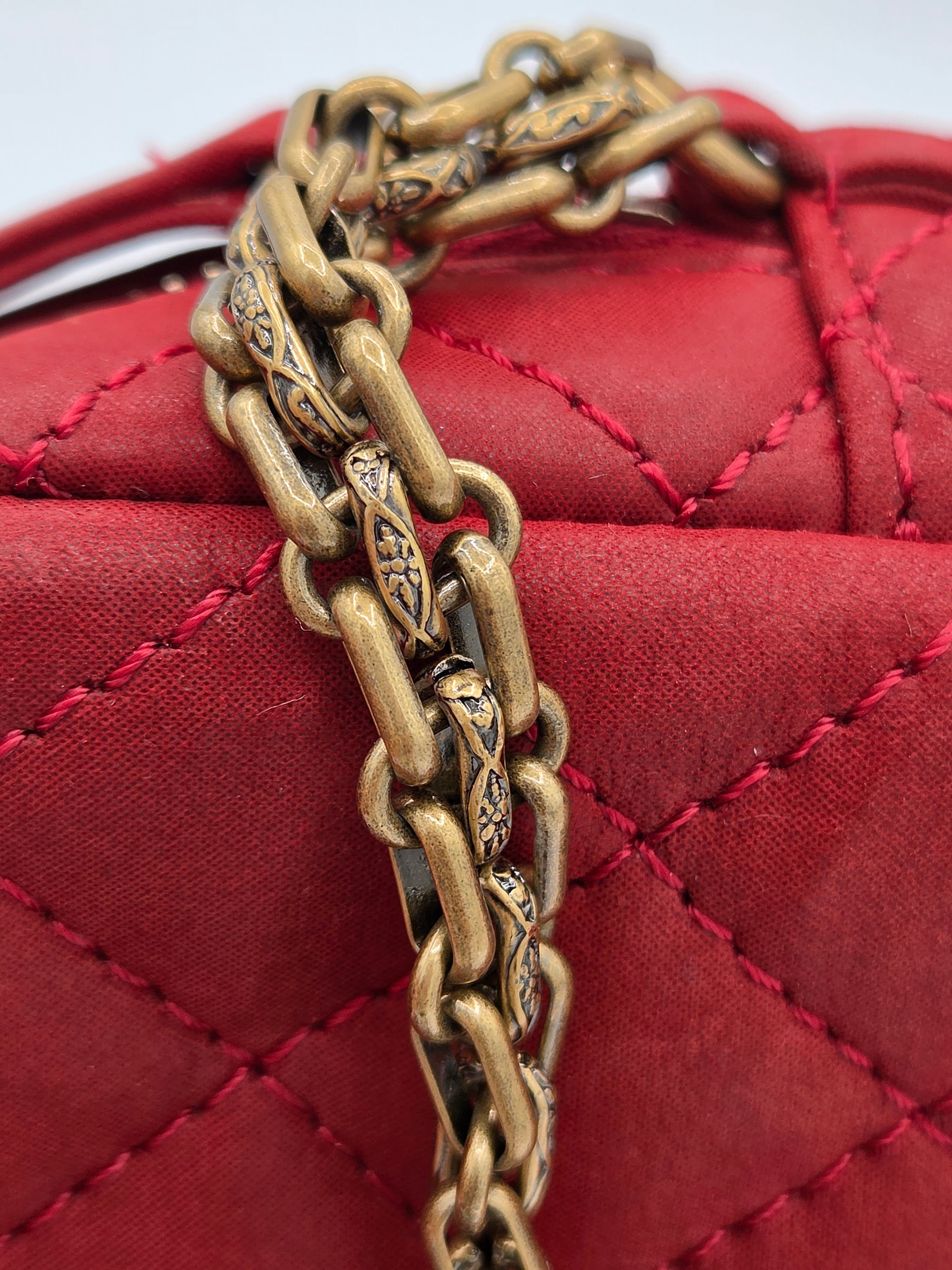 Red quilted handbag with a gold chain detail on a white background