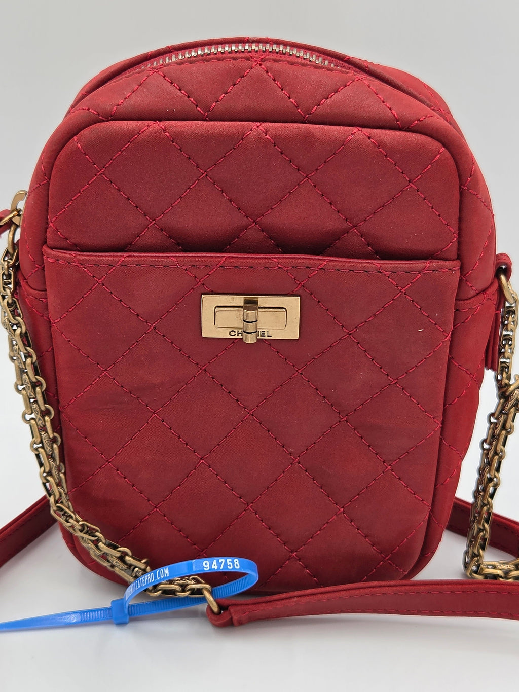 Red quilted handbag with gold chain strap on a light gray background