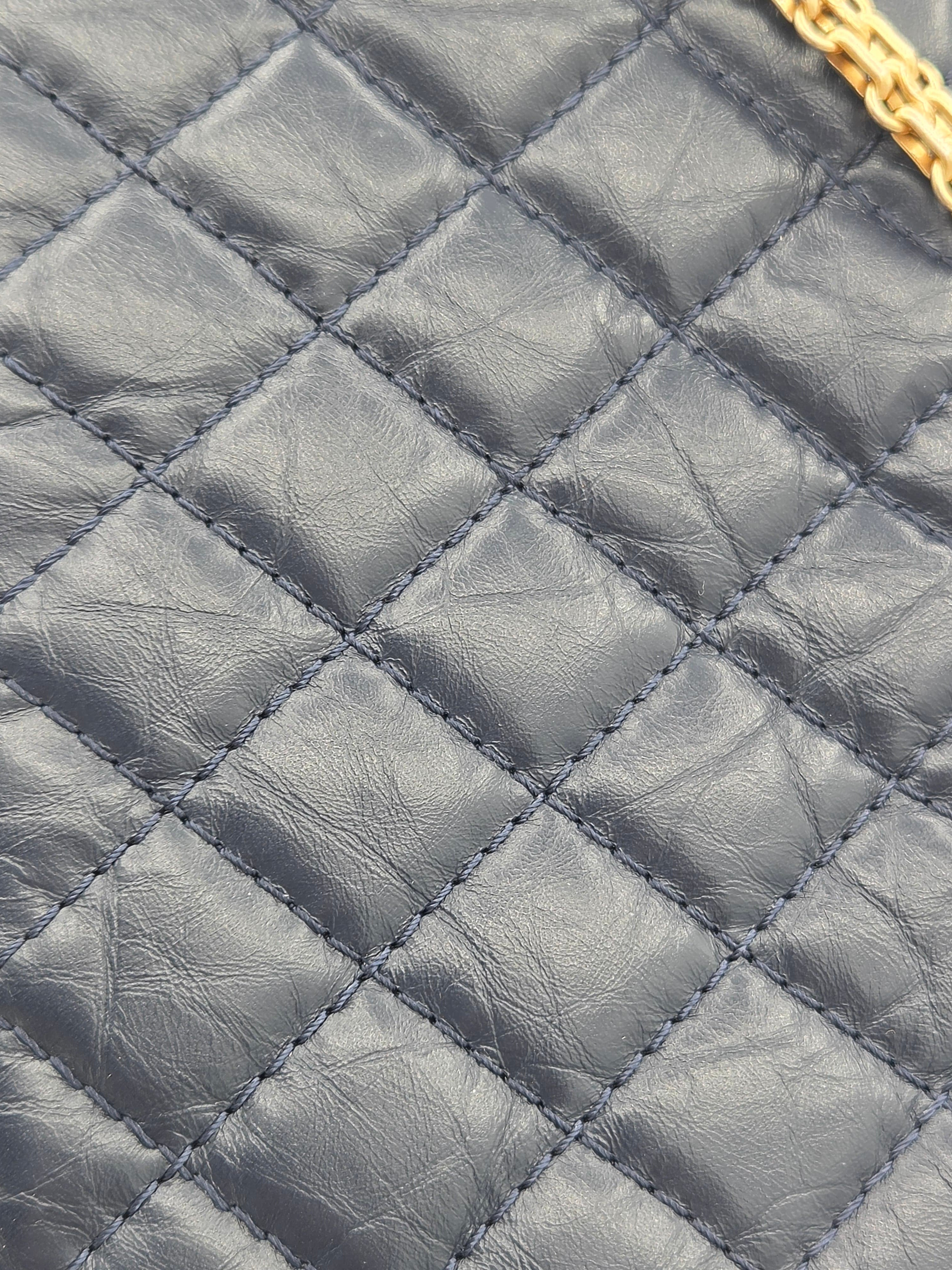 Close-up of a quilted gray leather handbag with gold zipper.