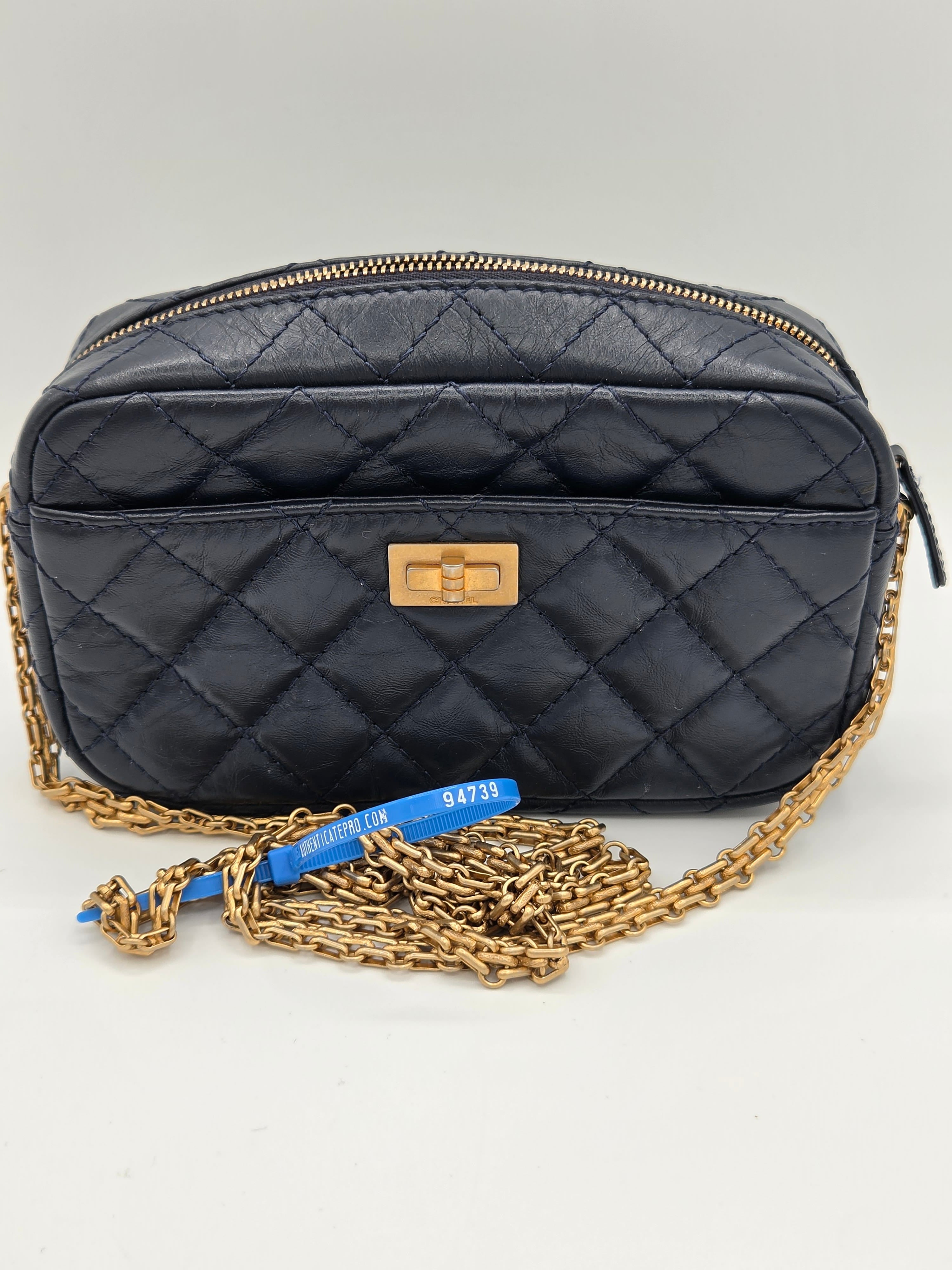 Black quilted handbag with gold chain strap on a light gray background