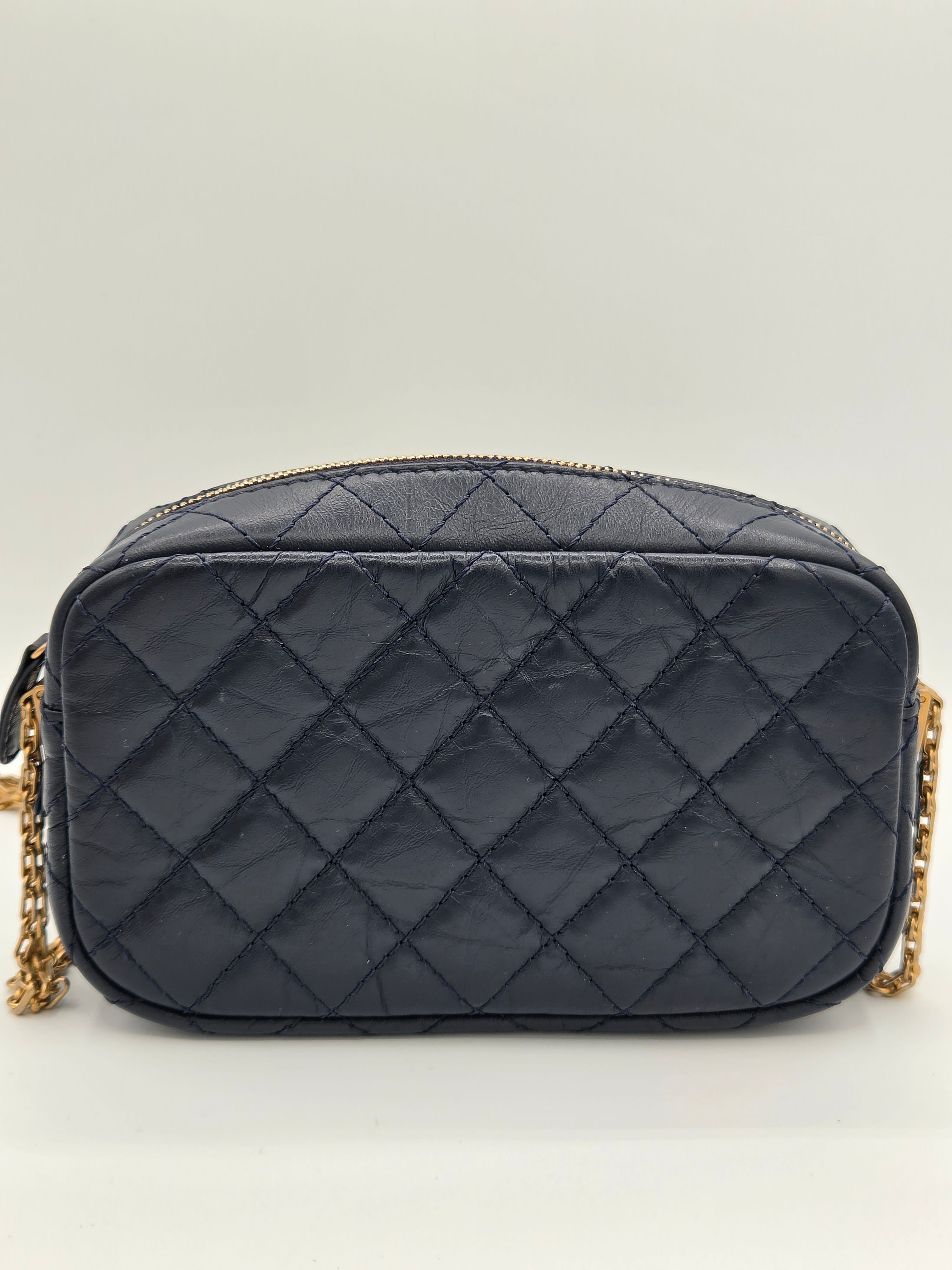 Quilted black handbag with gold chain on a light gray background