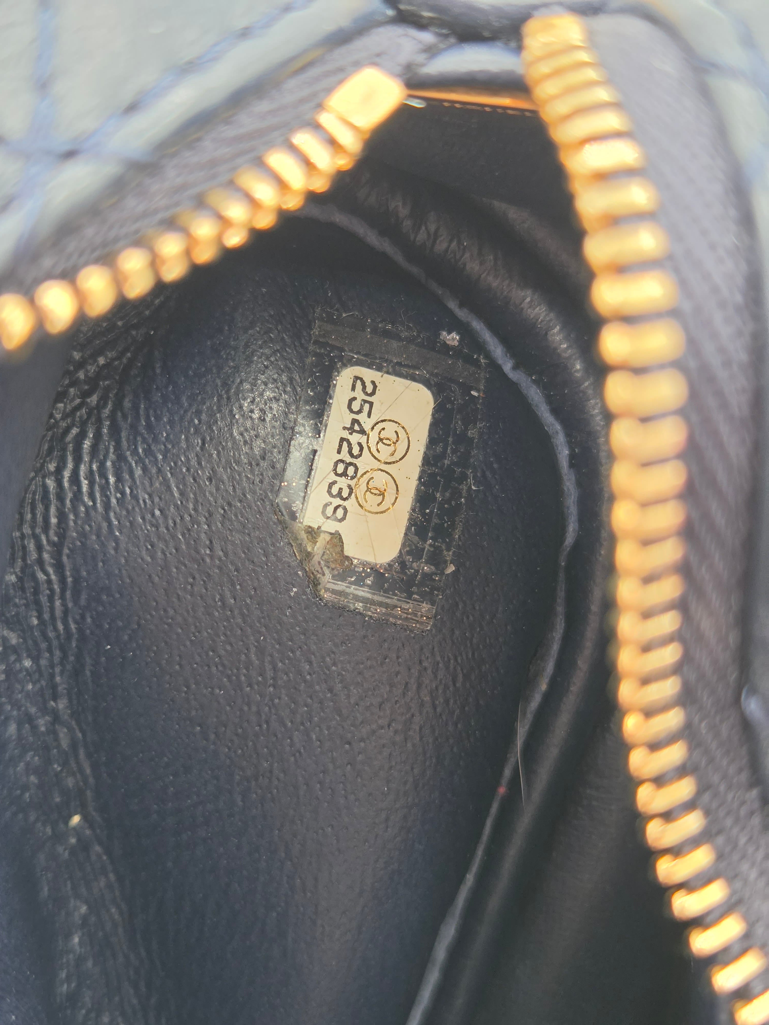 Close-up of a black leather product with gold zipper and visible serial number tag.