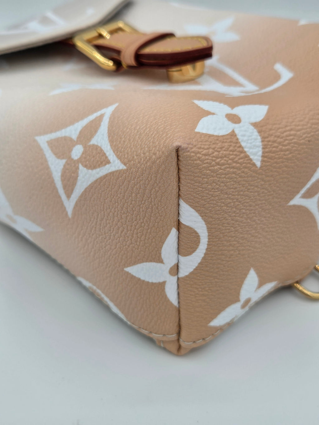 Close-up of a beige leather pouch with white floral patterns on a light gray background