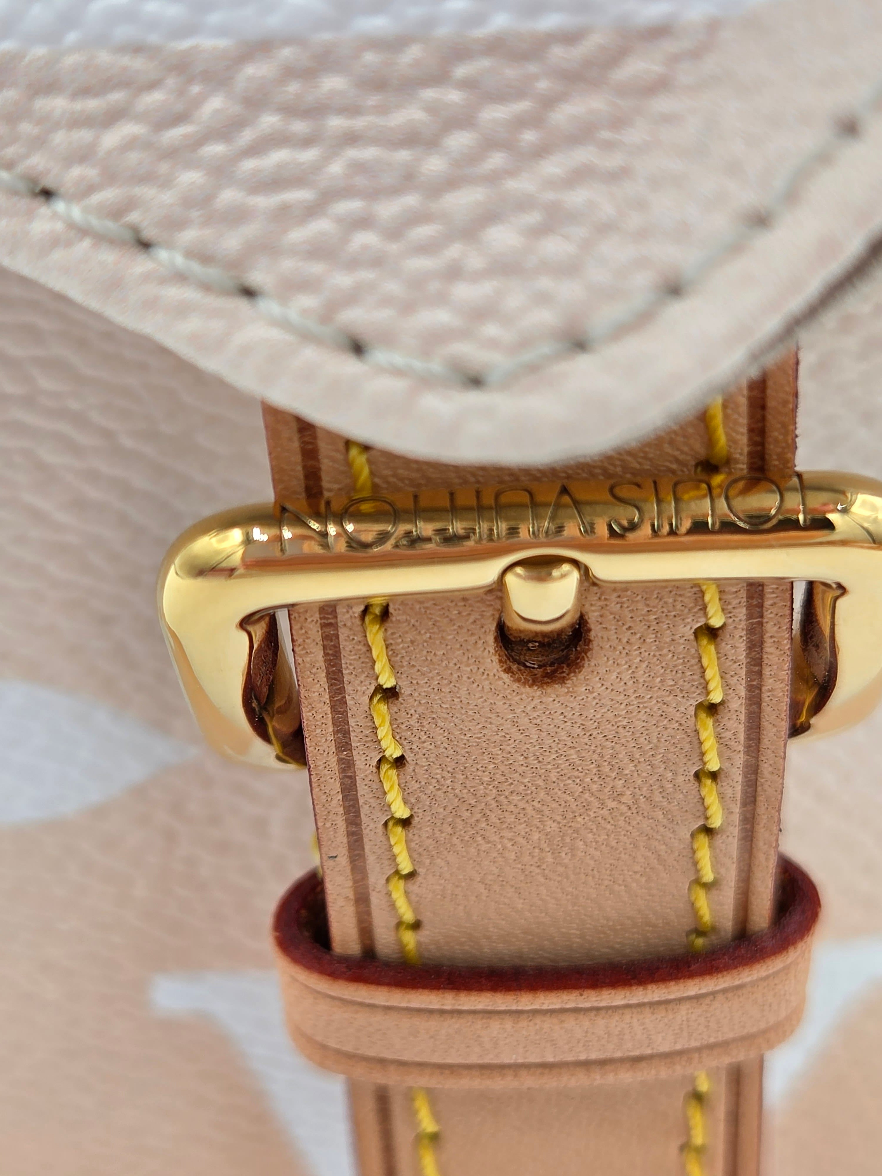 Close-up of a beige leather strap with gold buckle on a textured beige background