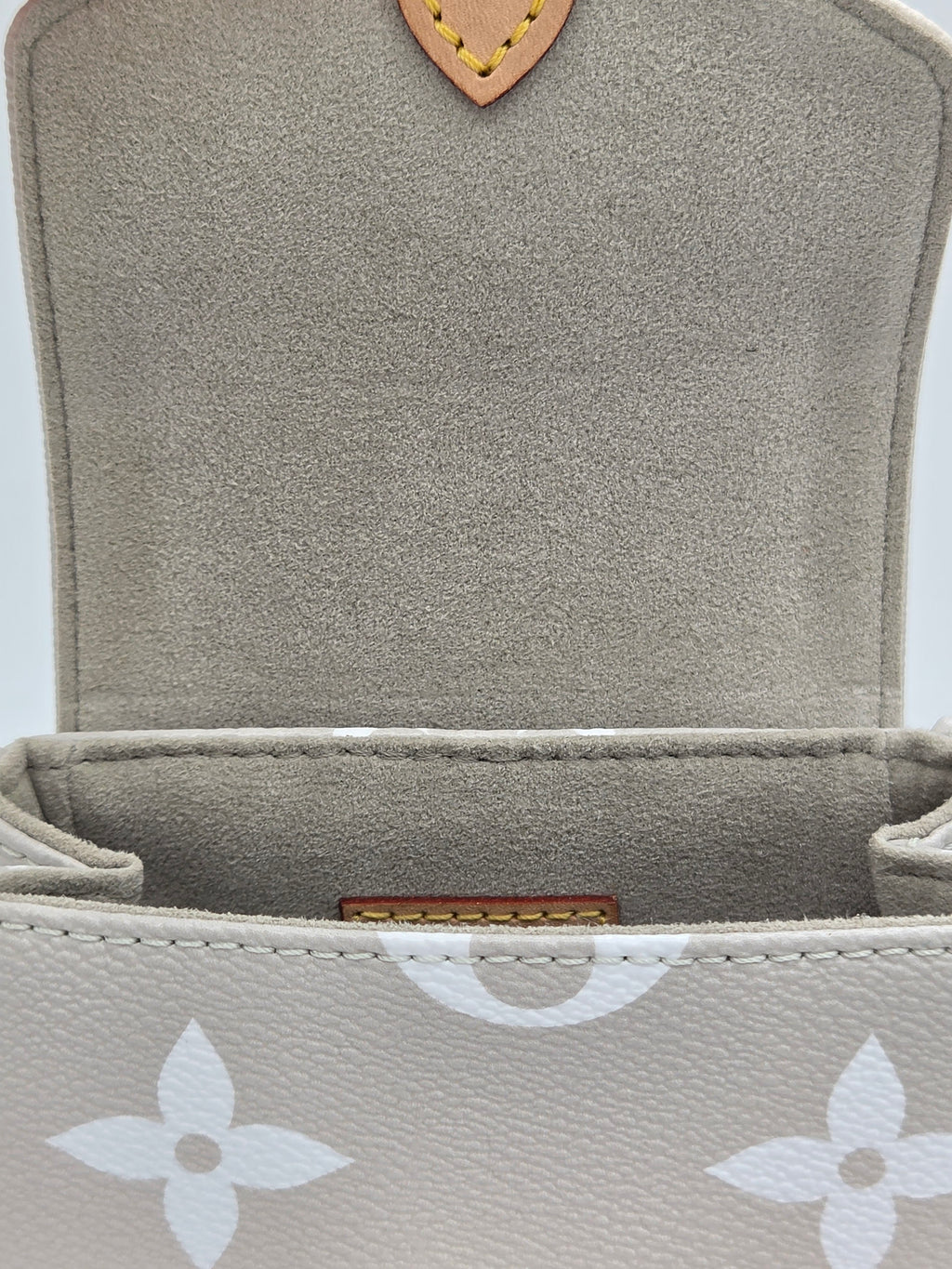 Close-up of a textured gray pouch with a brand logo on a white background