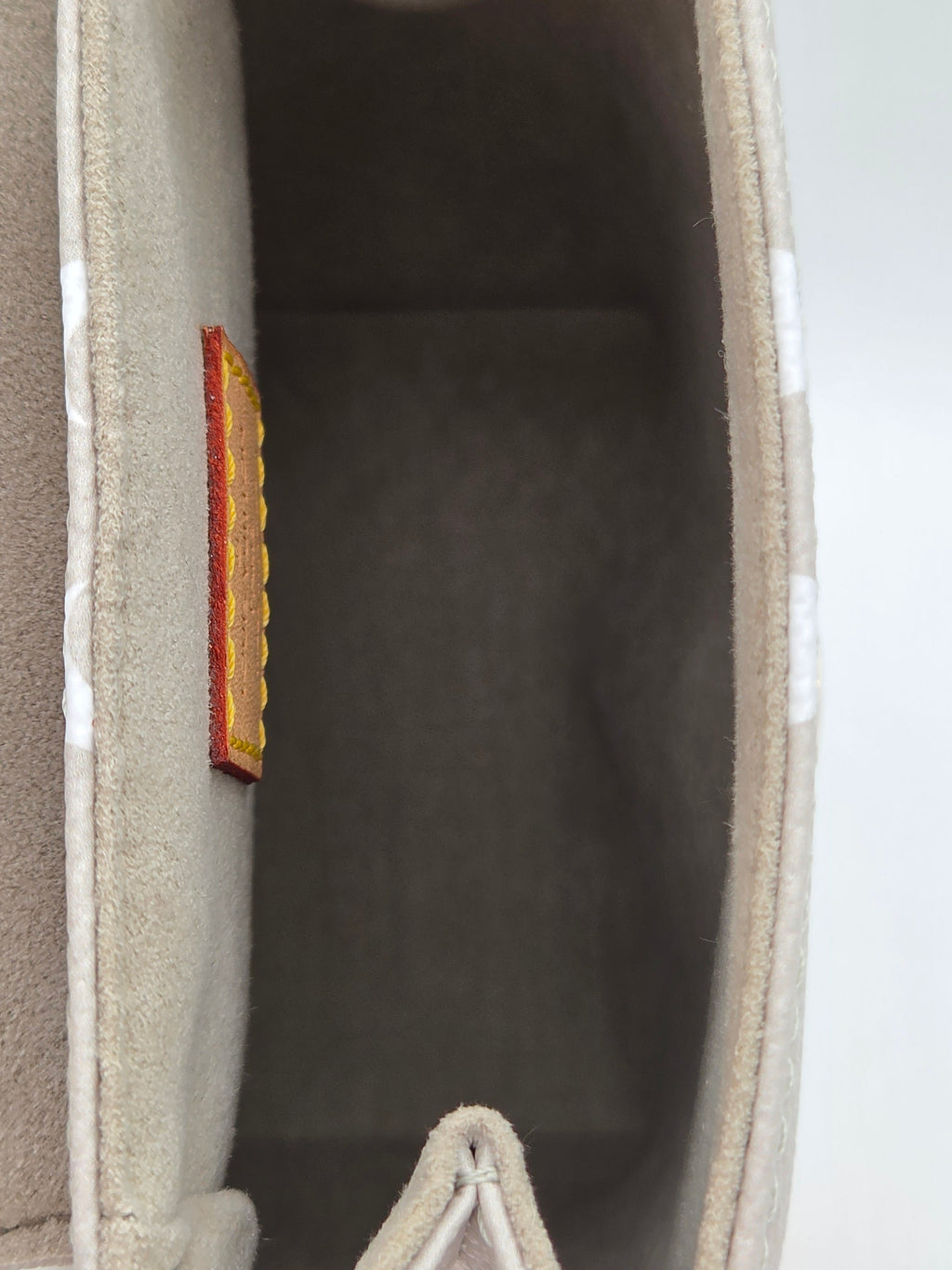 Close-up of a beige fabric surface with a small brown rectangular object on a light gray background