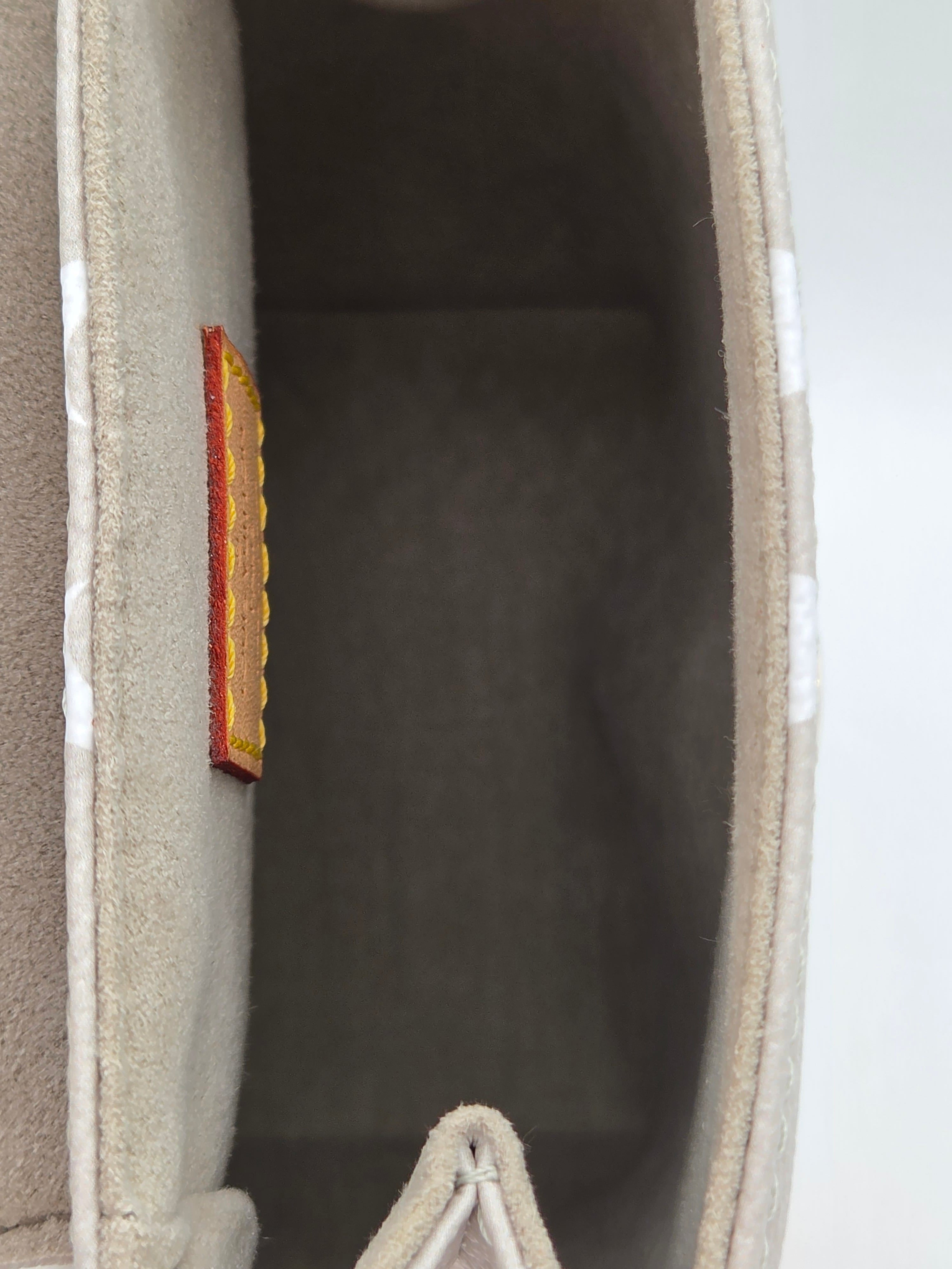Close-up of a beige fabric surface with a small brown rectangular object on a light gray background