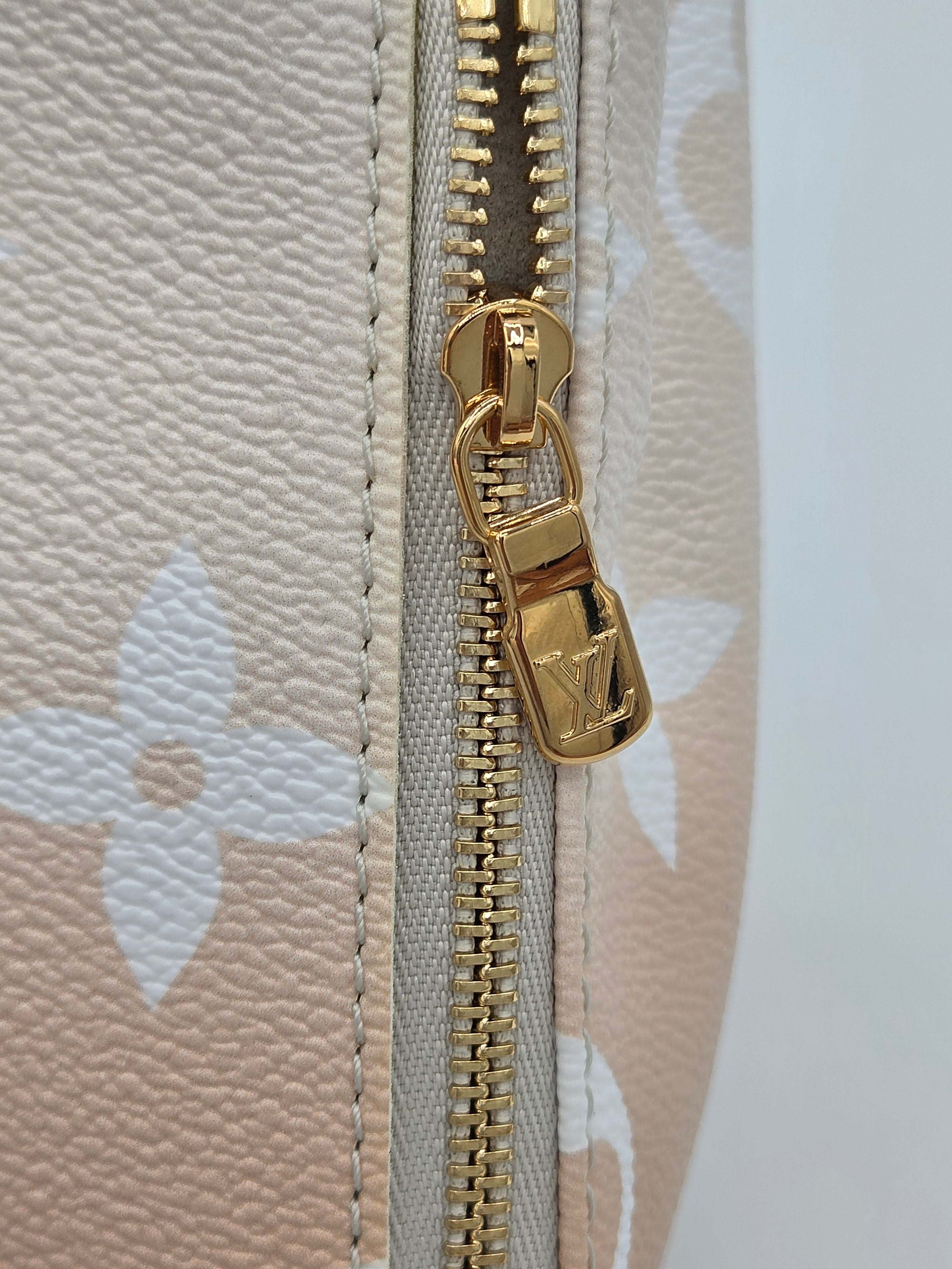 Close-up of a gold zipper on a beige fabric background