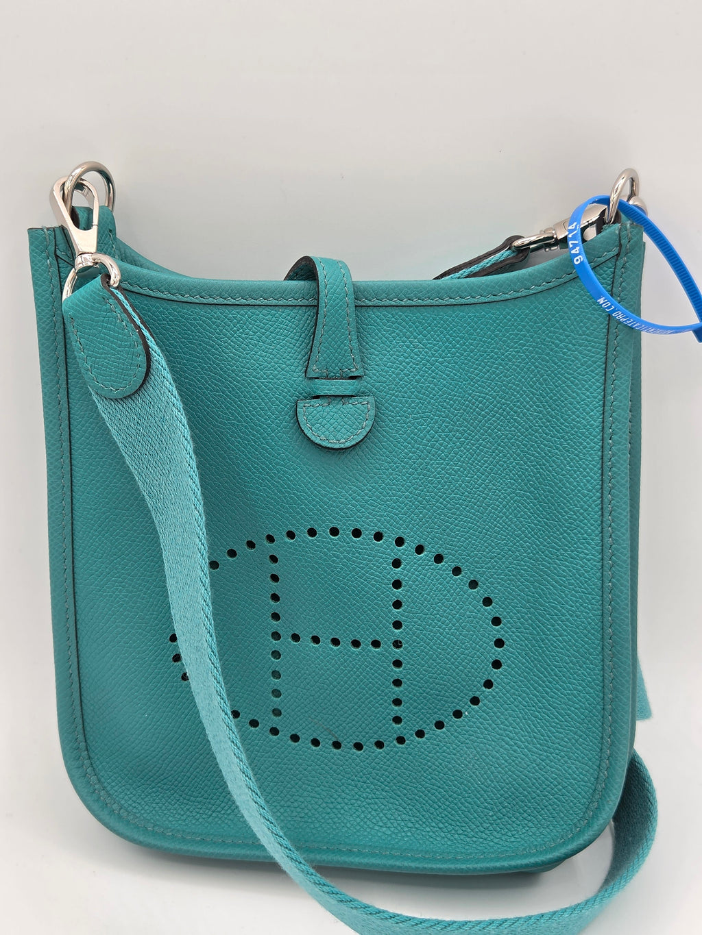 Teal handbag with a brand logo on a light gray background