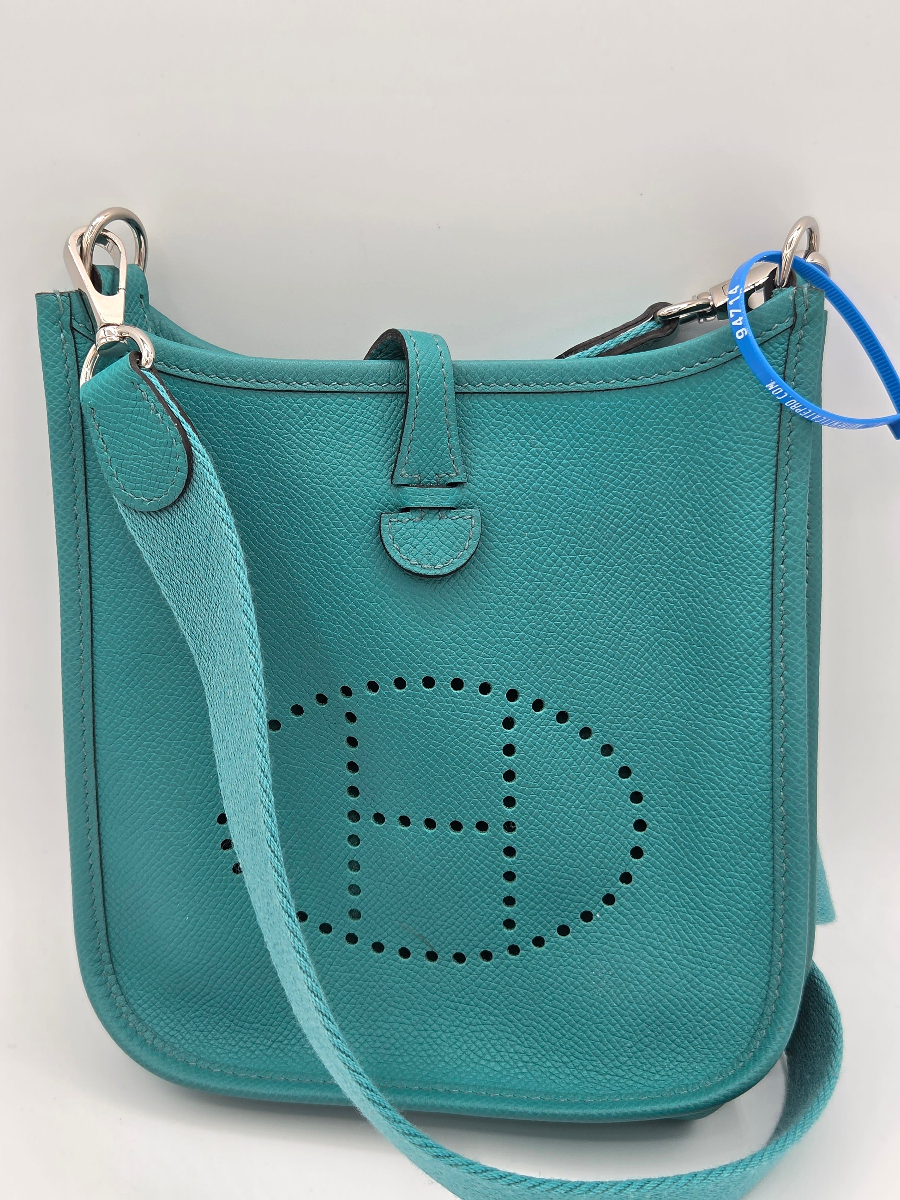 Teal handbag with a brand logo on a light gray background