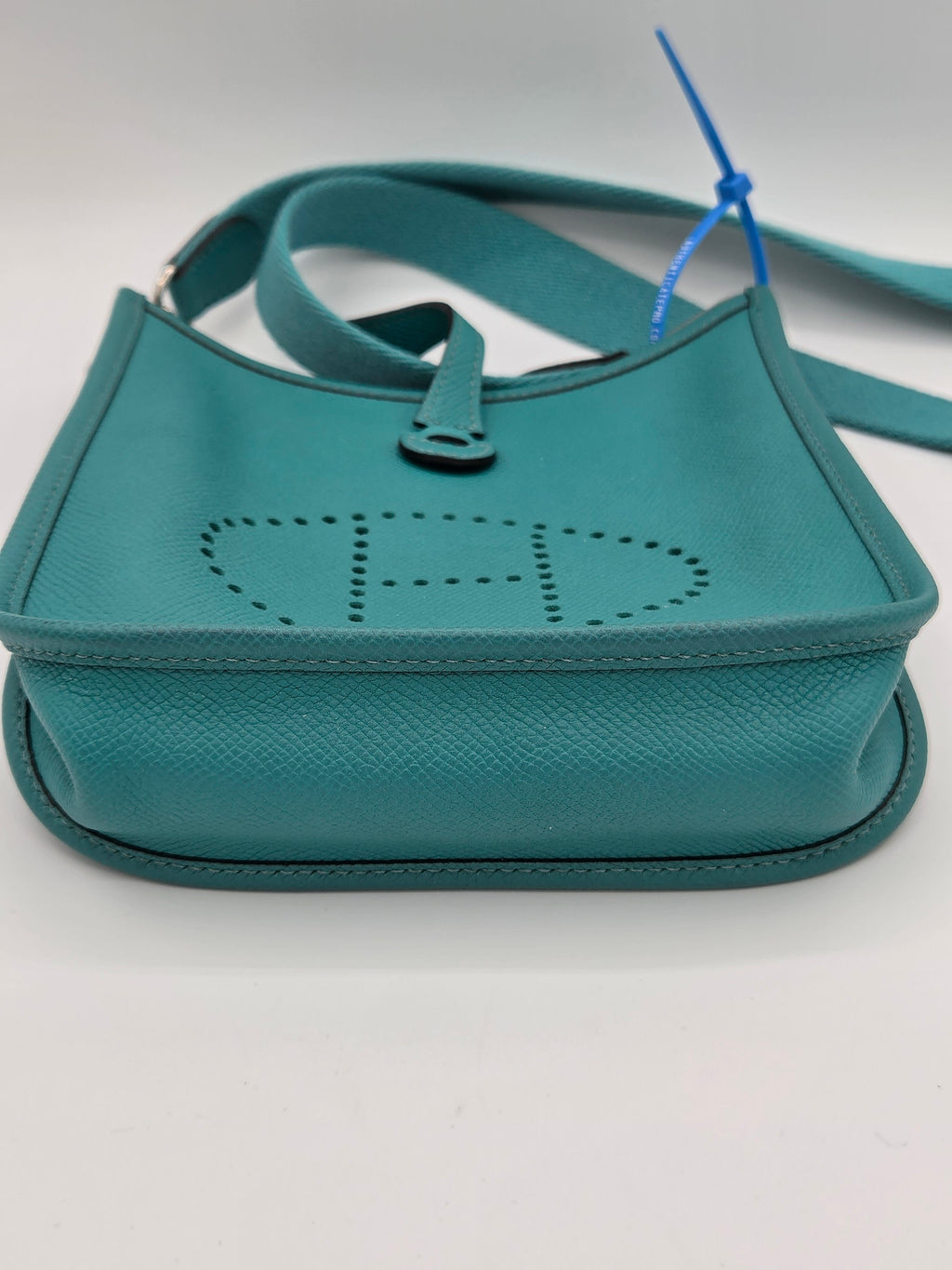 Teal handbag with a visible brand logo on a light gray background