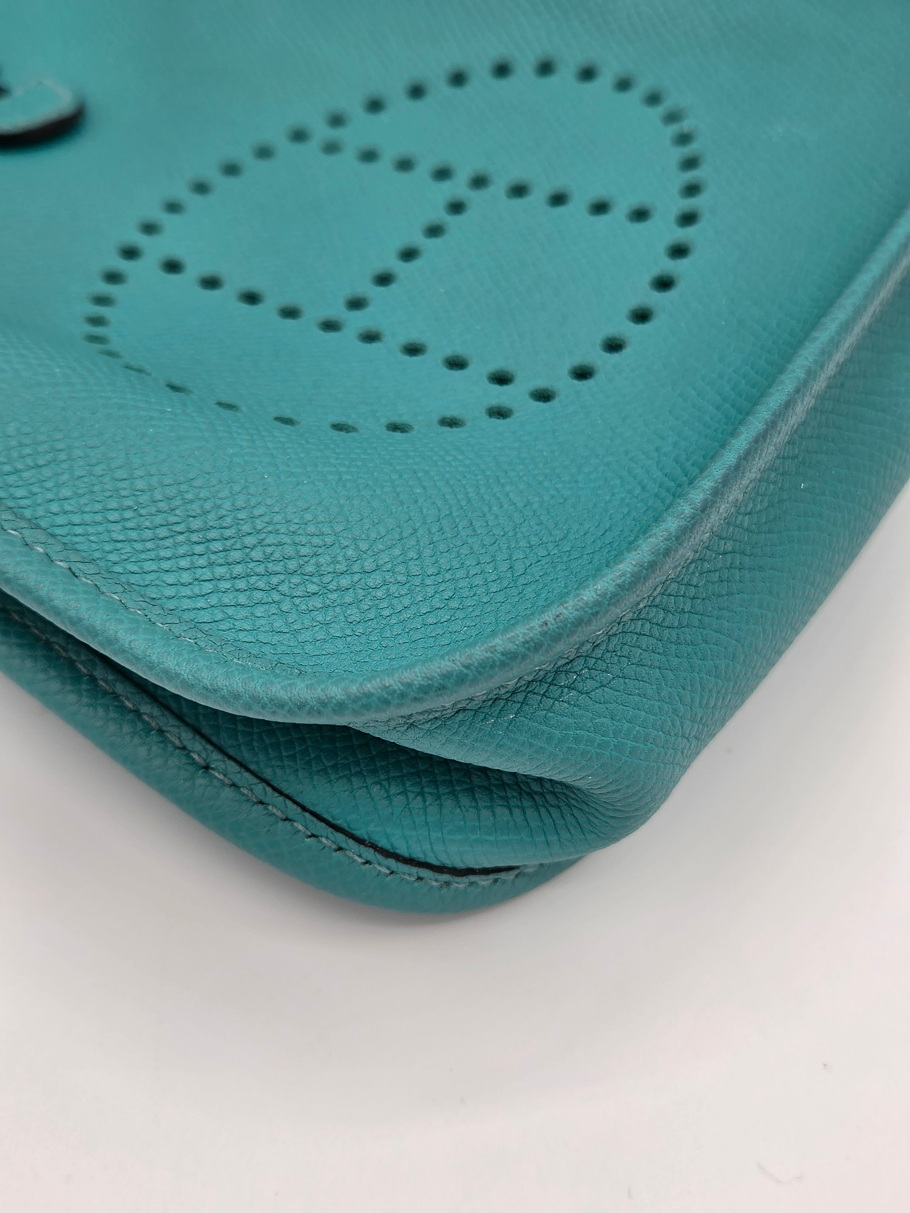 Close-up of a teal pouch with a brand logo on a white background